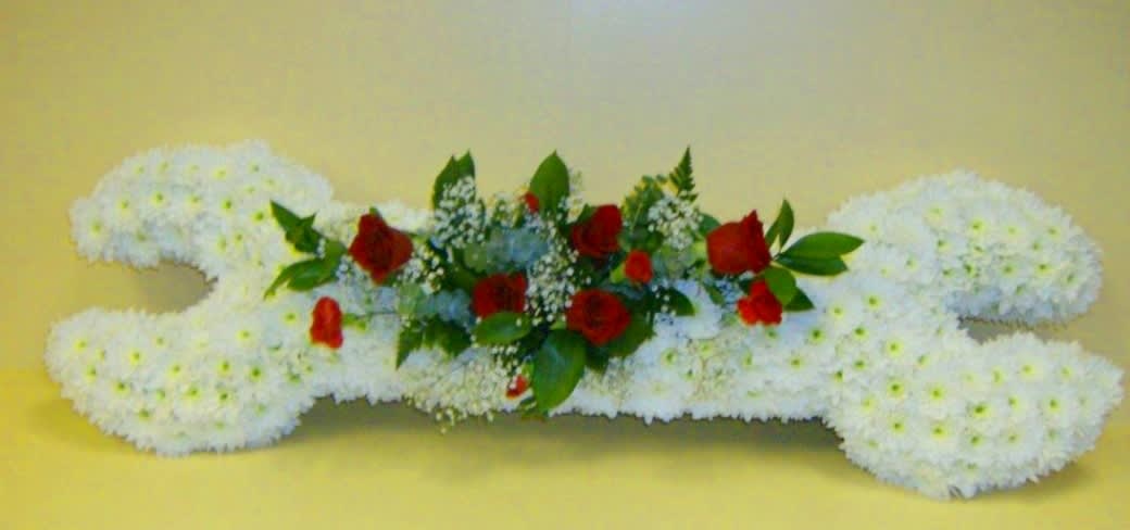 White floral arrangement shaped like a bone with red roses in the center