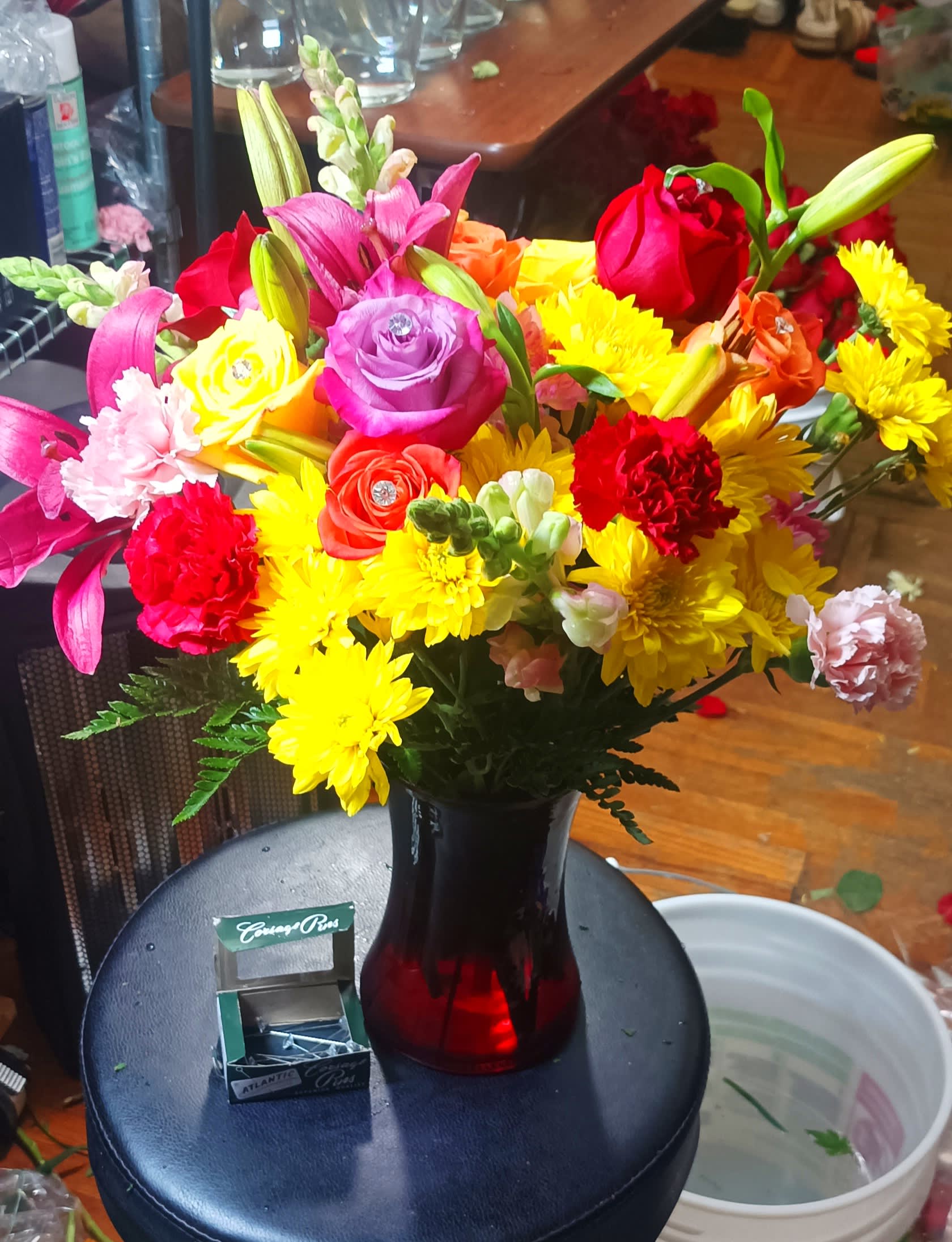 Colorful bouquet of roses, lilies, and chrysanthemums in a red vase