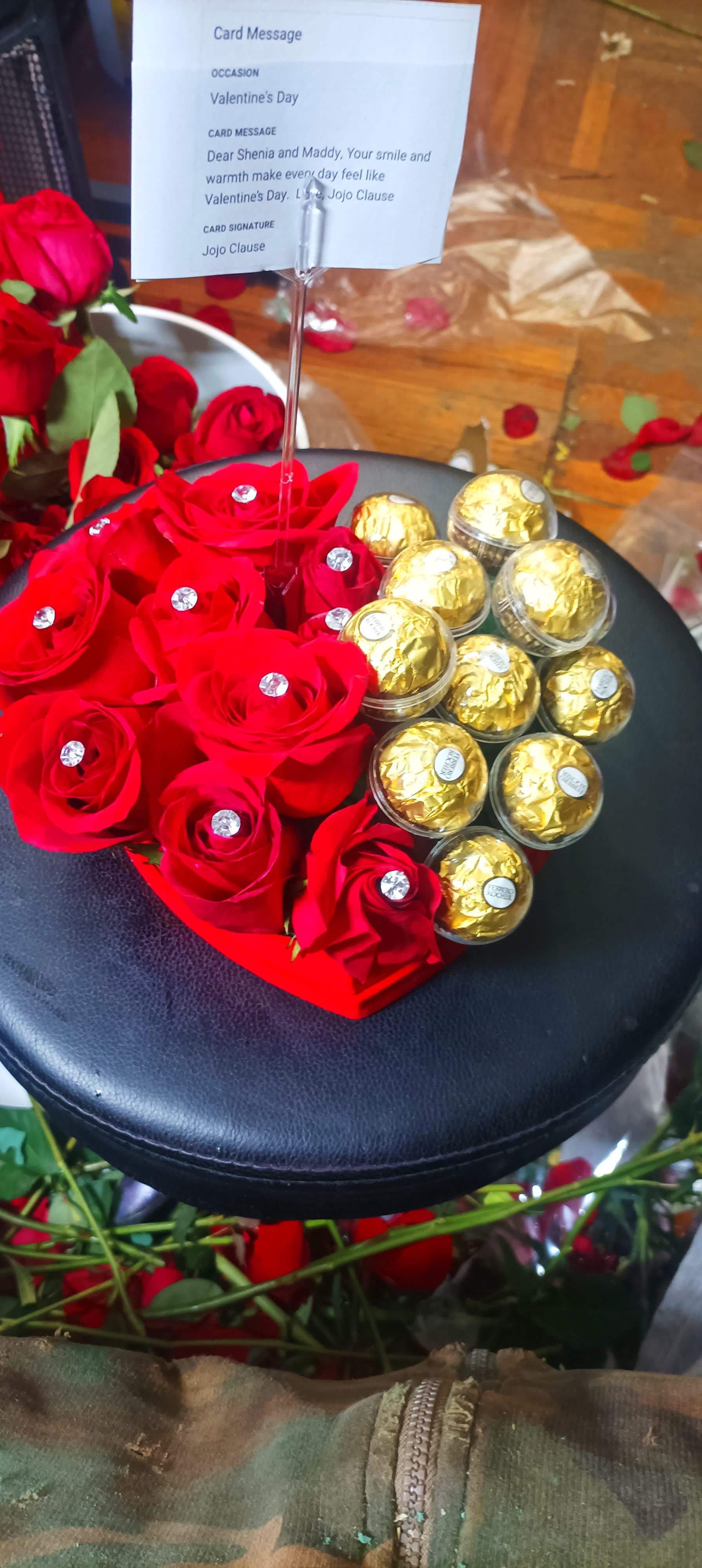 Red roses arranged with gold-wrapped chocolates in a heart-shaped box