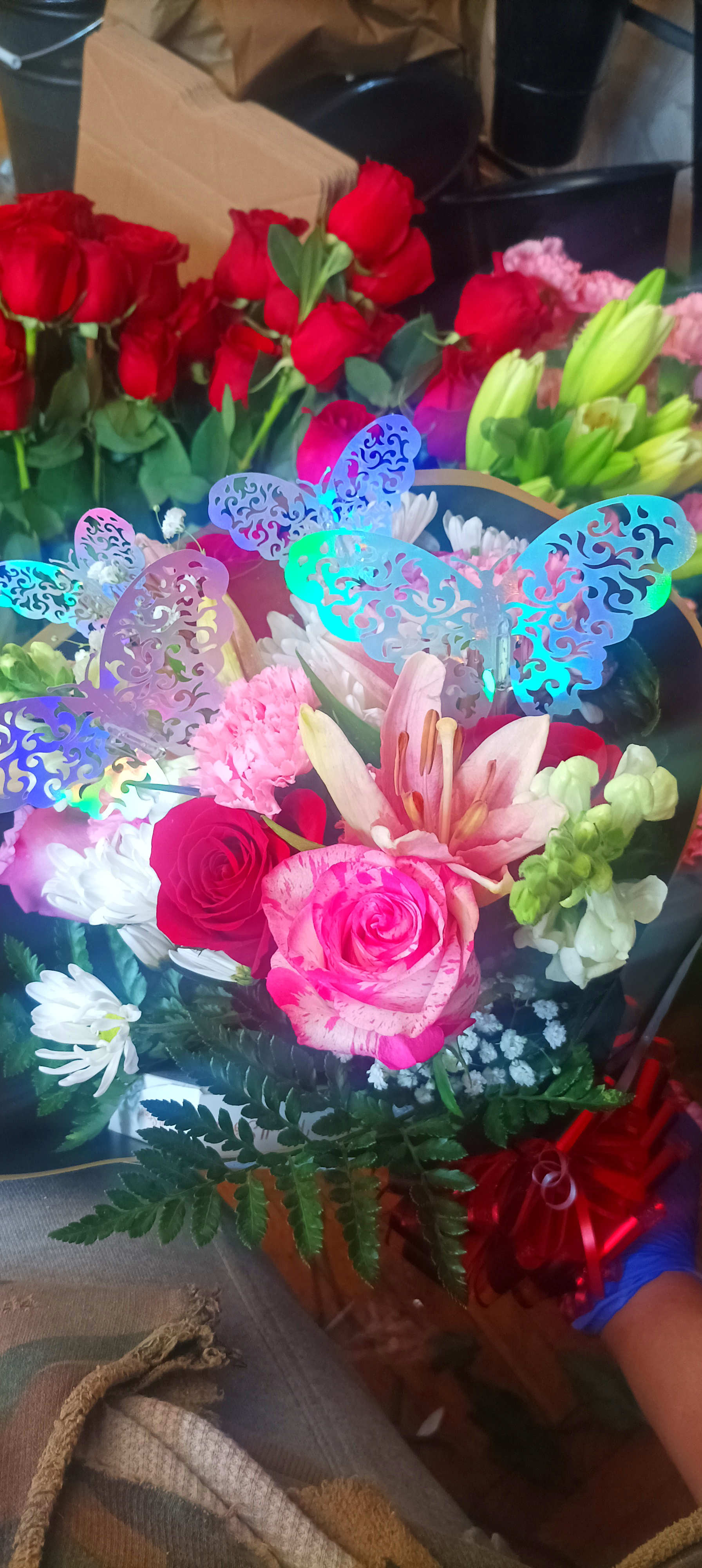 Bouquet of pink and red roses with lilies and white daisies, decorated with butterfly picks