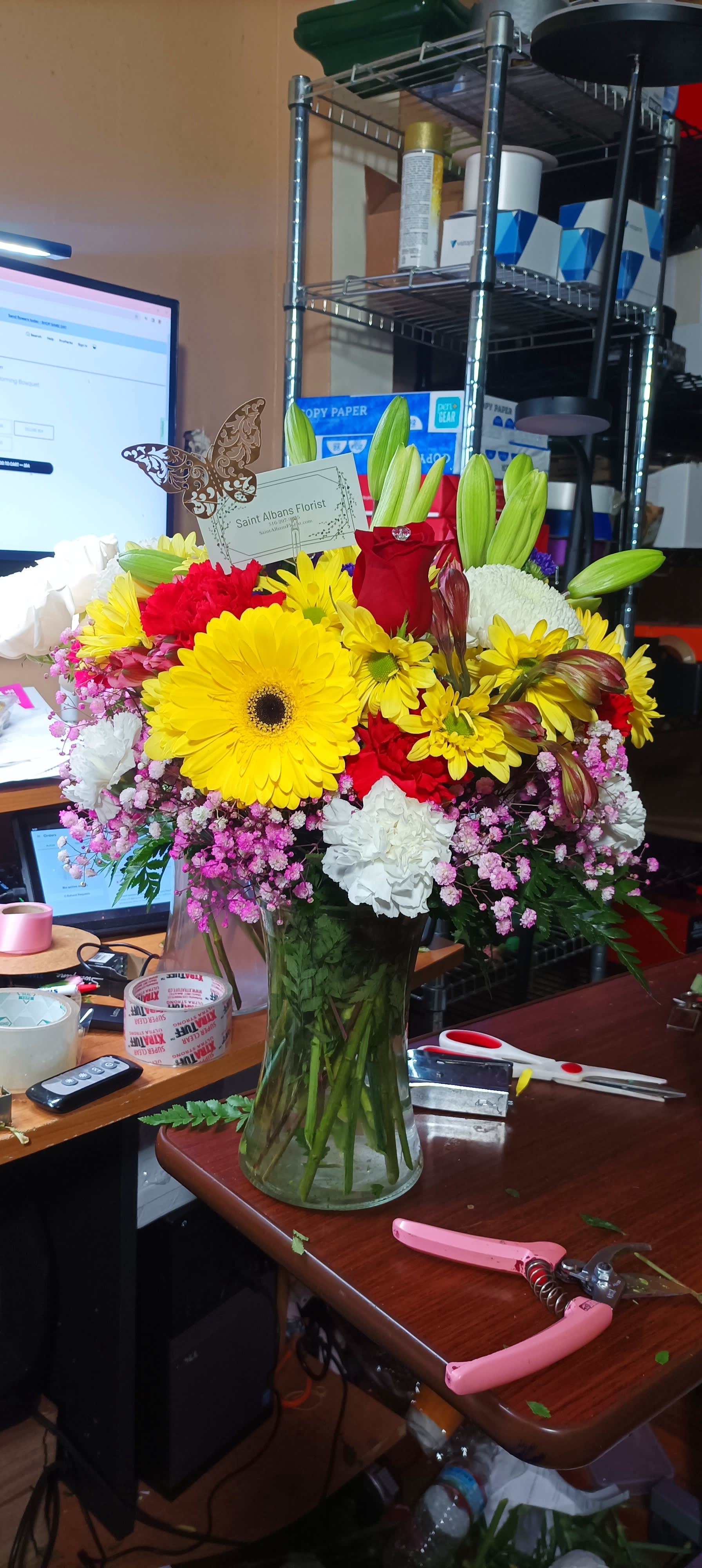 Mixed bouquet in a clear glass vase with yellow, red, and white flowers