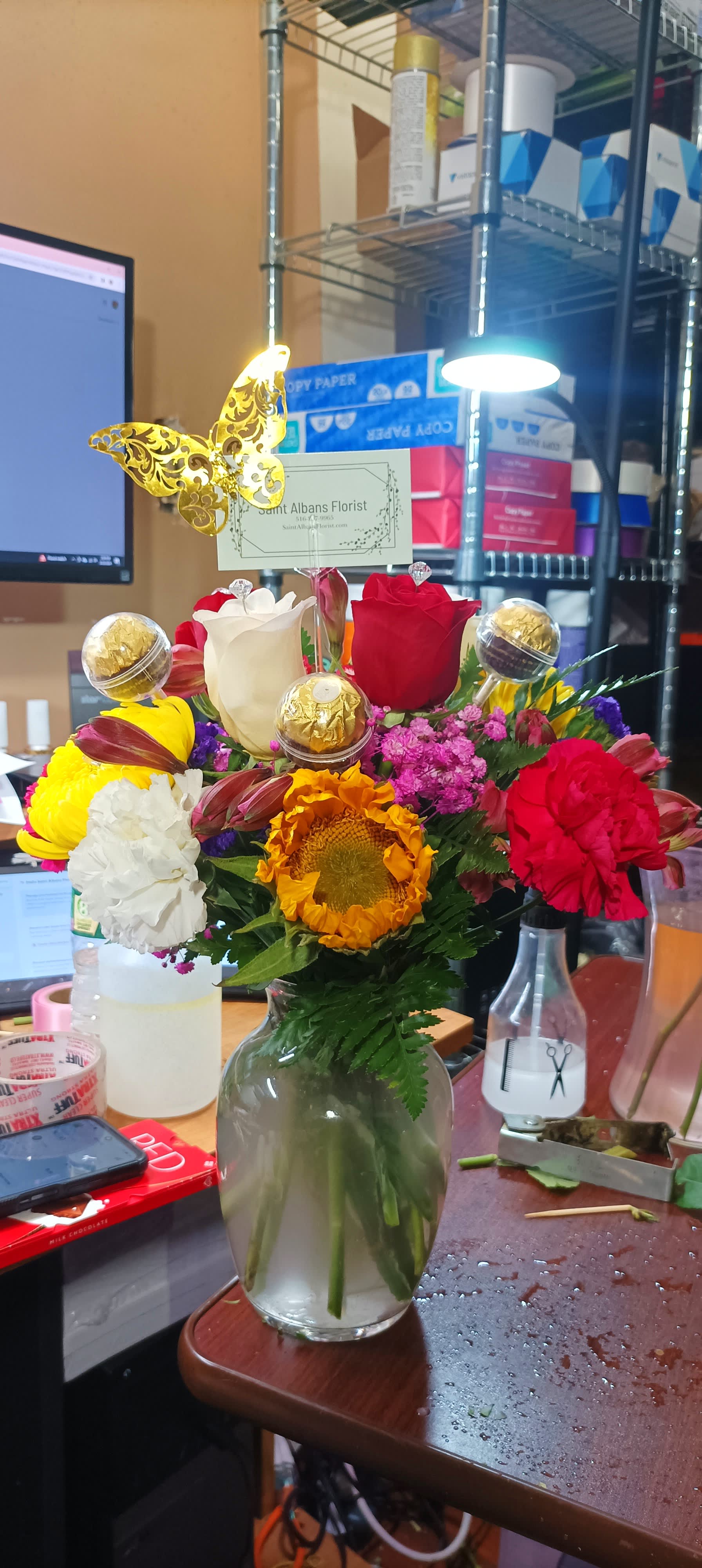 Mixed bouquet in a glass vase with roses, carnations, and a sunflower