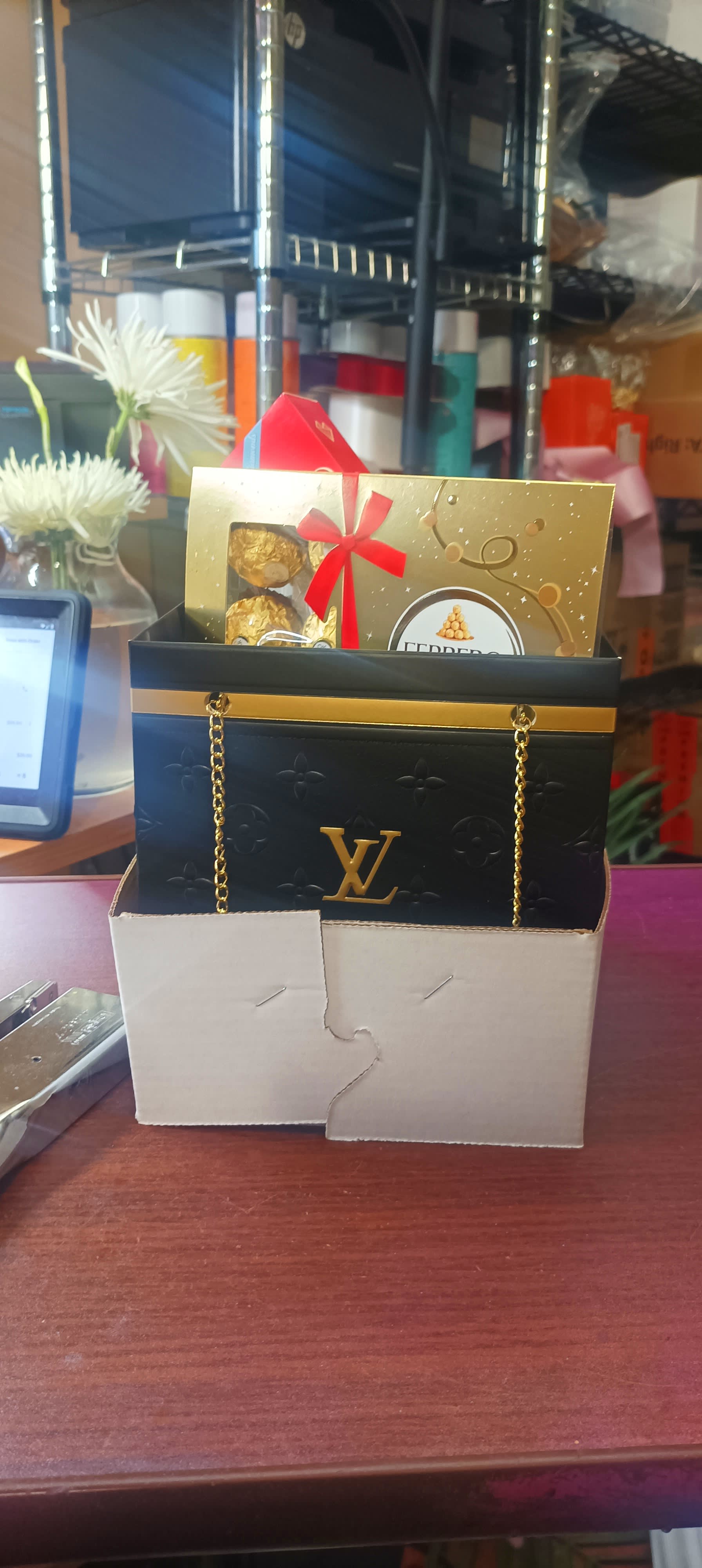 Gift bag with chocolates and a gold card, with white flowers in the background.