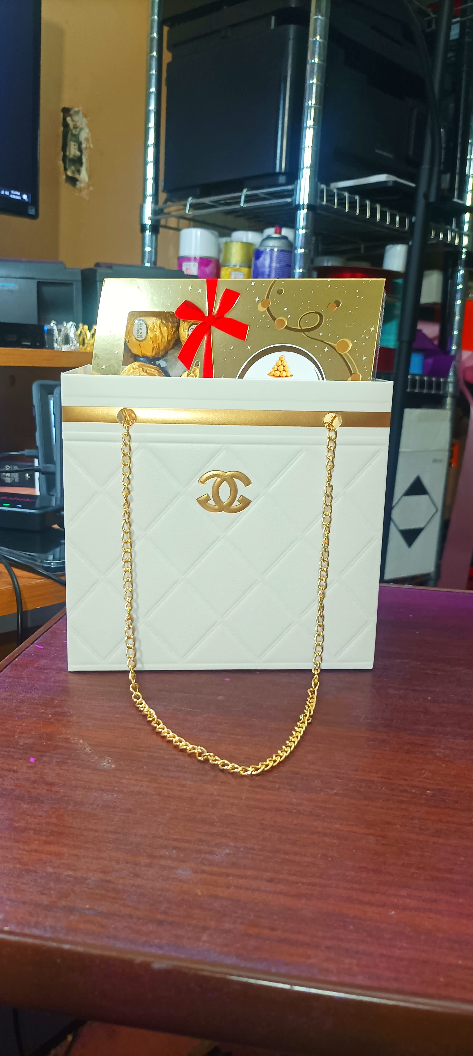 White gift bag with gold chain handles and a gold gift box inside