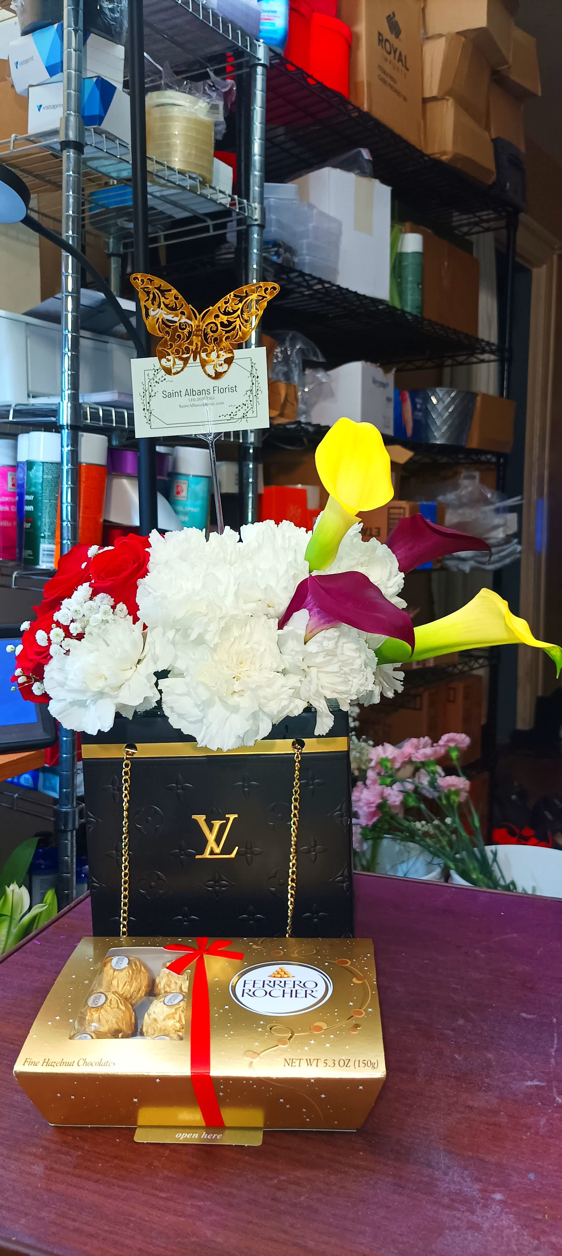 Flower arrangement in a black gift bag with calla lilies and roses, plus a chocolate box