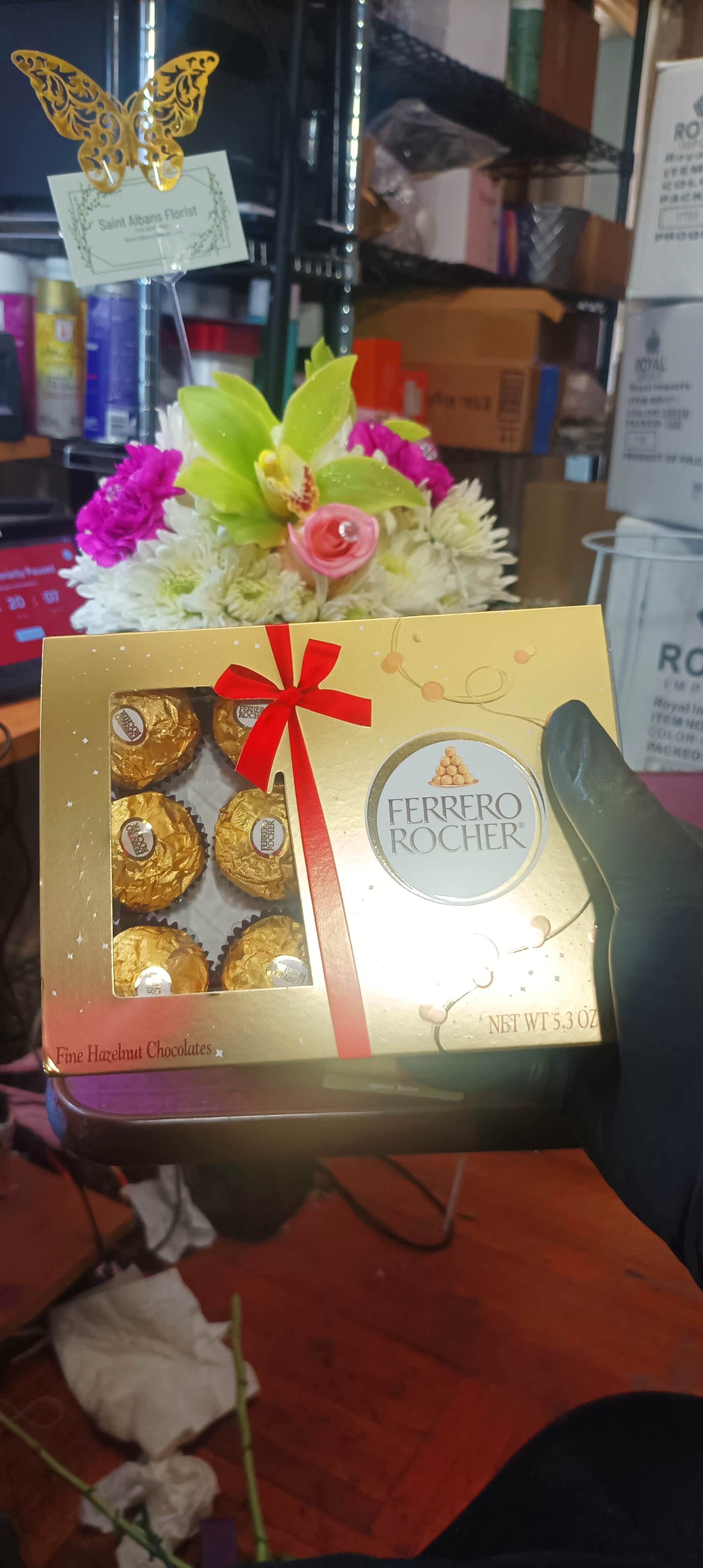 Ferrero Rocher chocolate box held in front of a small flower arrangement