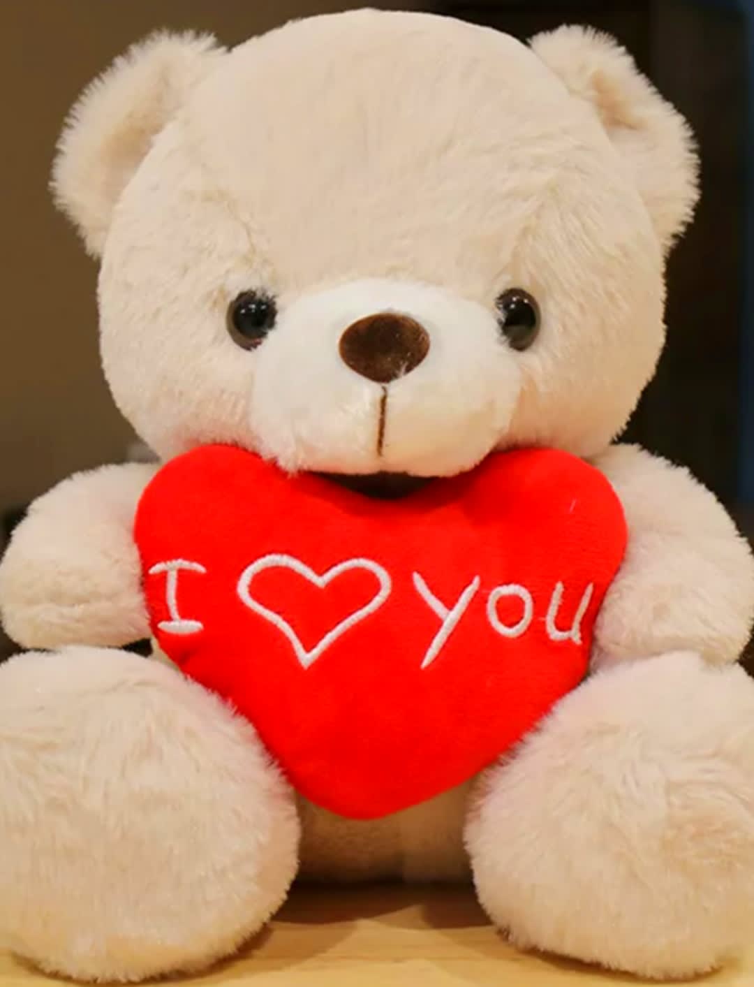 White teddy bear holding a red heart with "I love you" text
