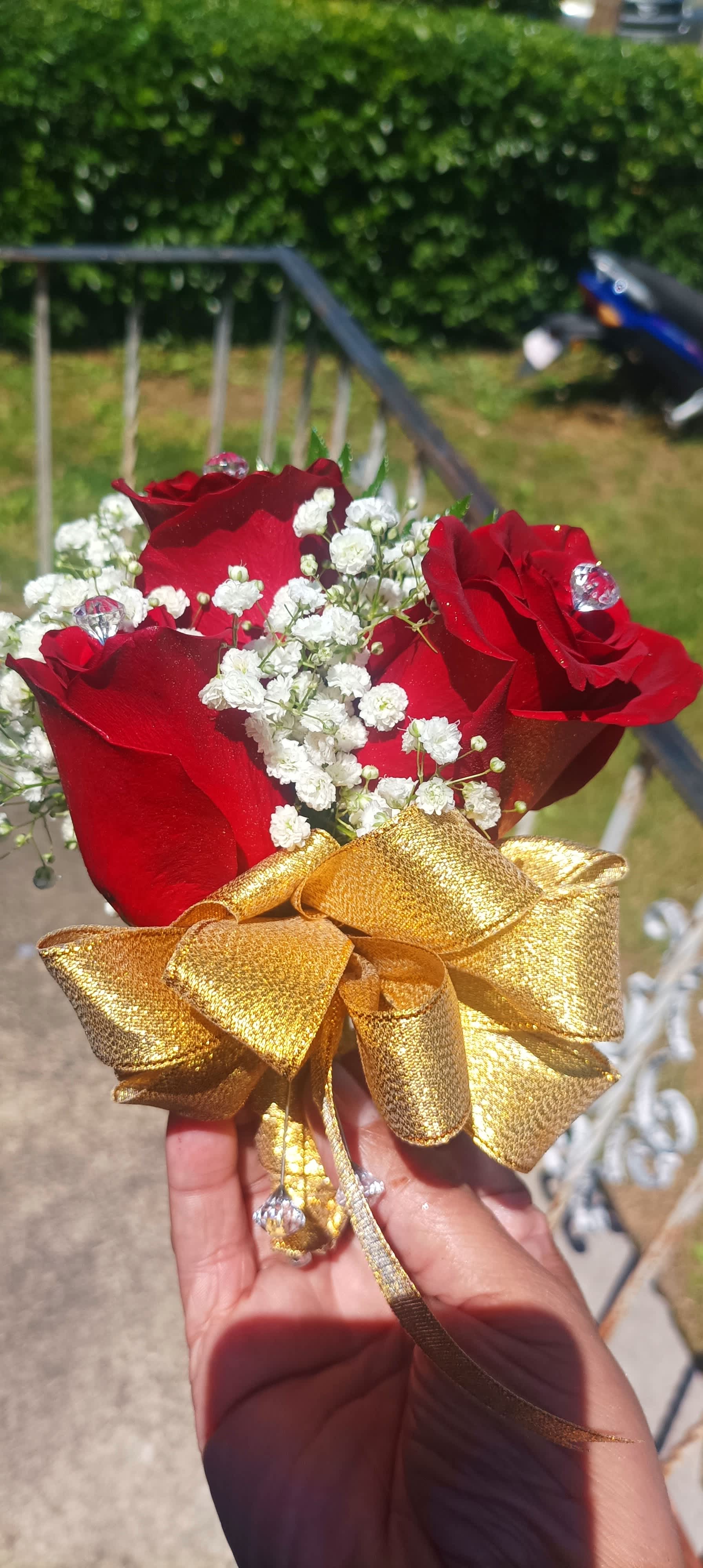 Small bouquet of red roses with white baby's breath and a gold ribbon