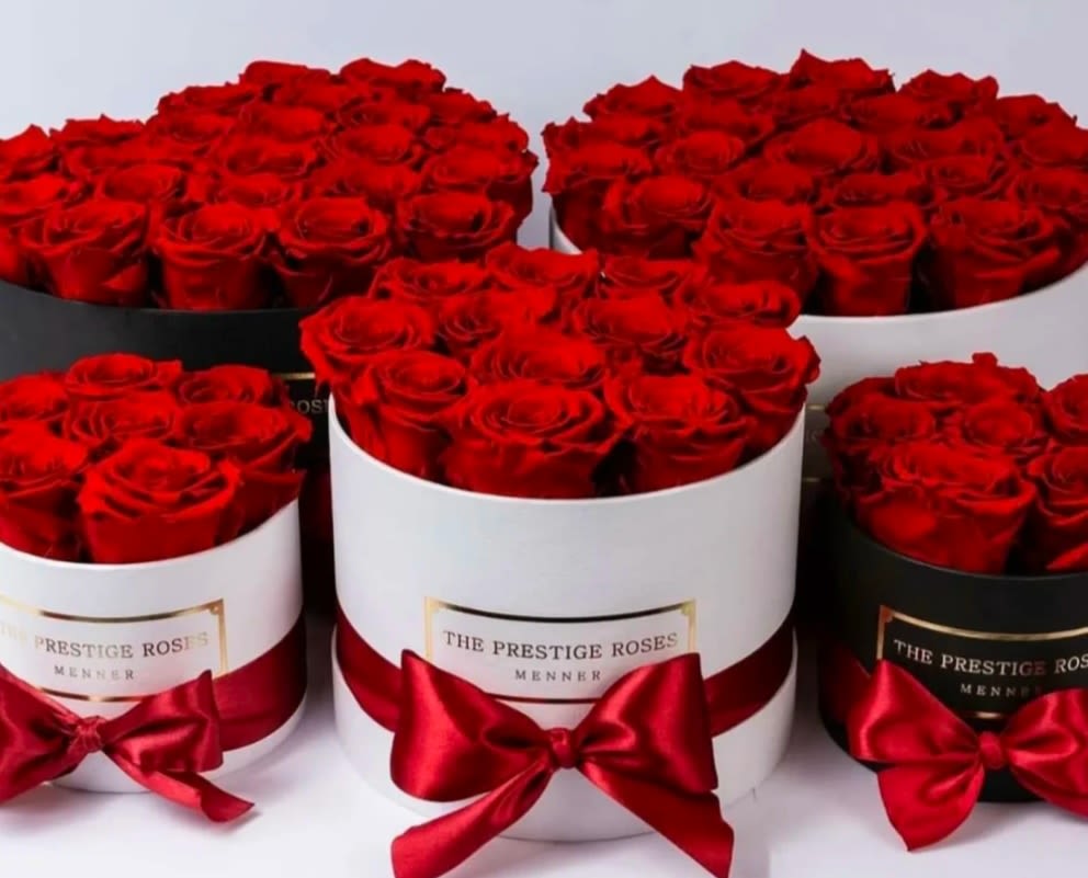 Red roses arranged in round hat boxes with satin bows