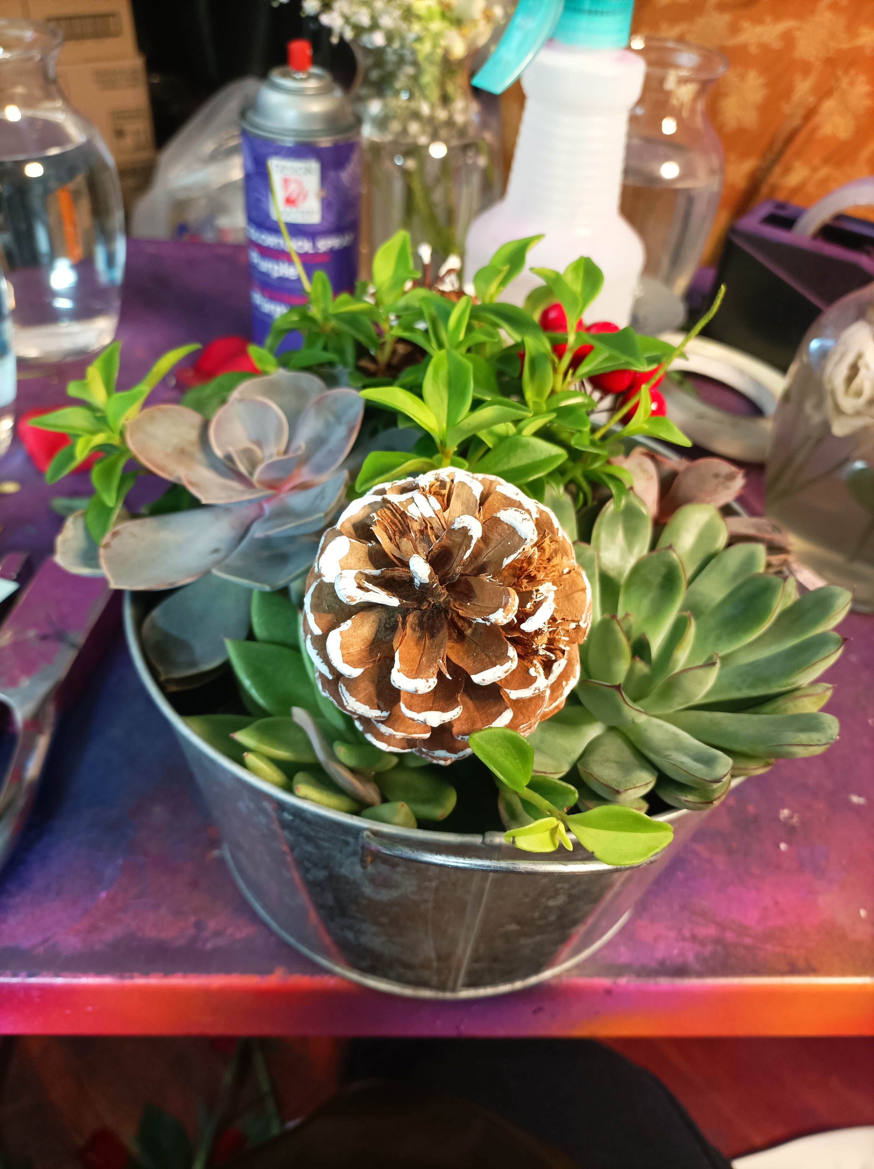 Succulent arrangement in a metal bucket with a painted pinecone centerpiece