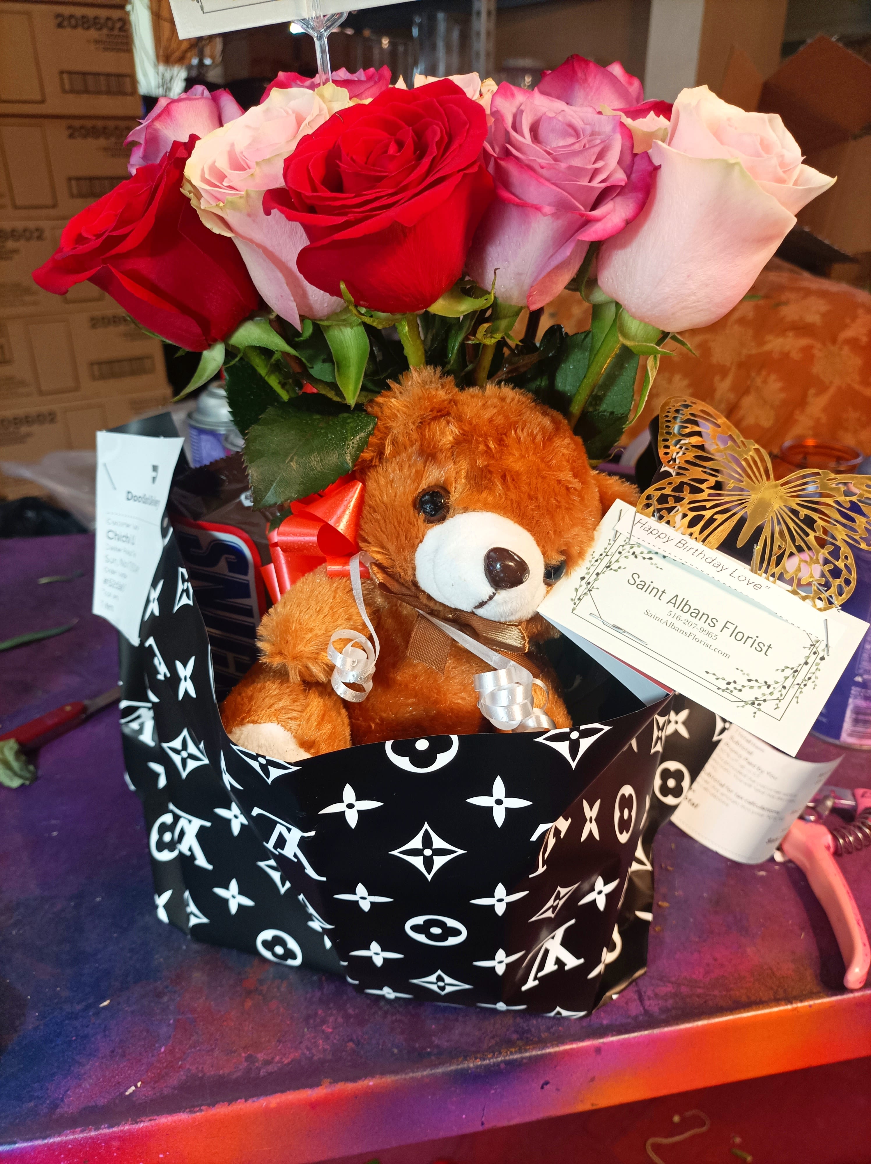 Bouquet of red, pink, and lavender roses with a teddy bear in a gift wrap