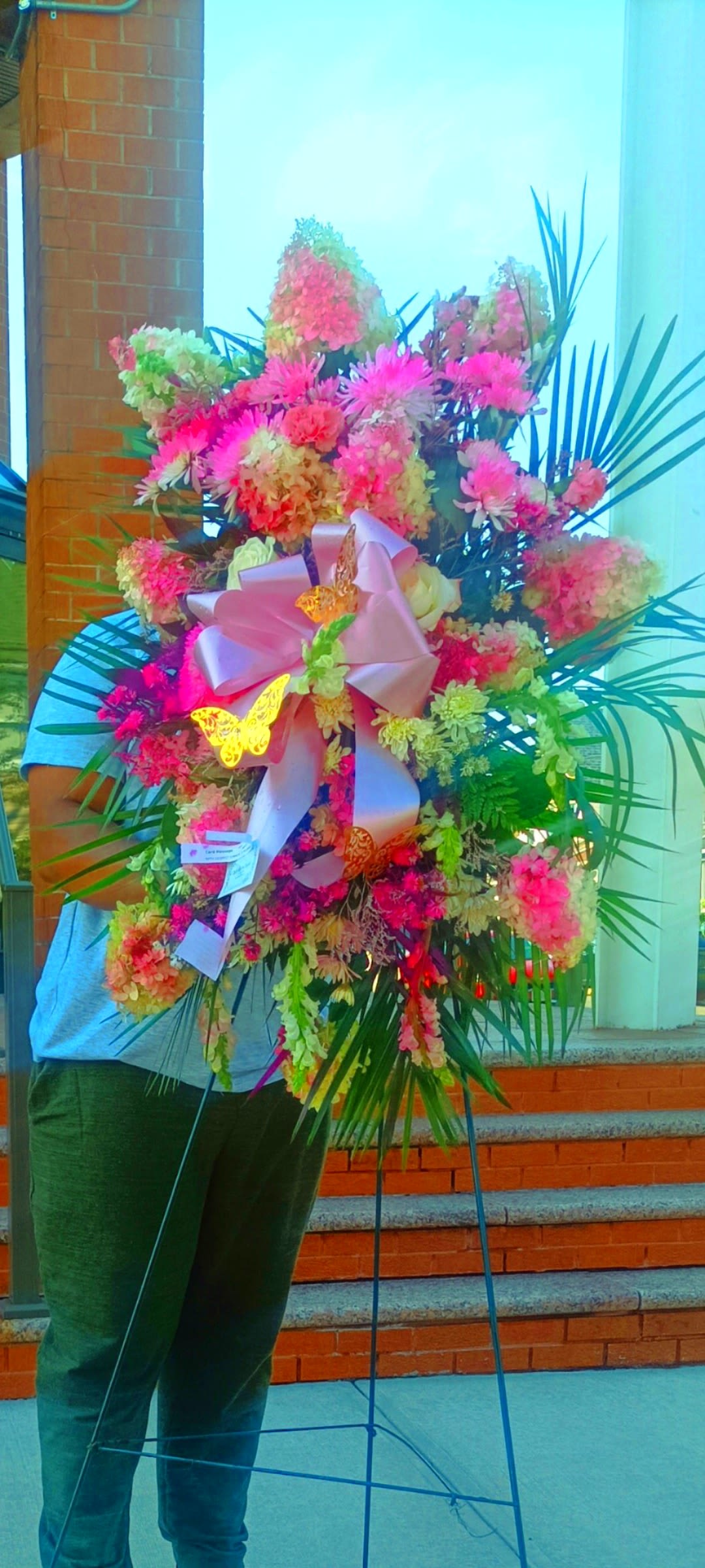 Large standing floral spray with pink and peach blooms on an easel