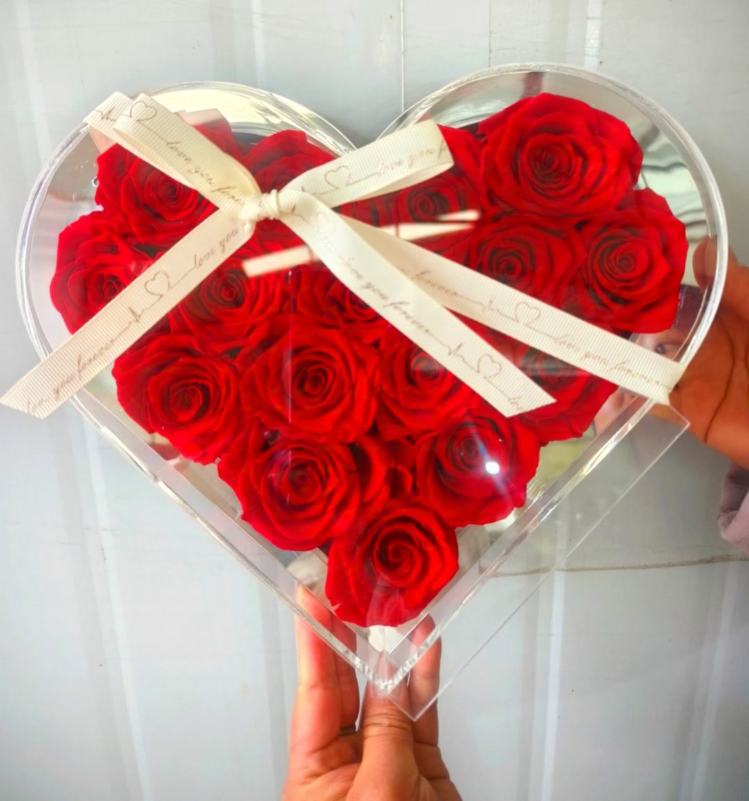 Heart-shaped box filled with red roses and tied with a white ribbon
