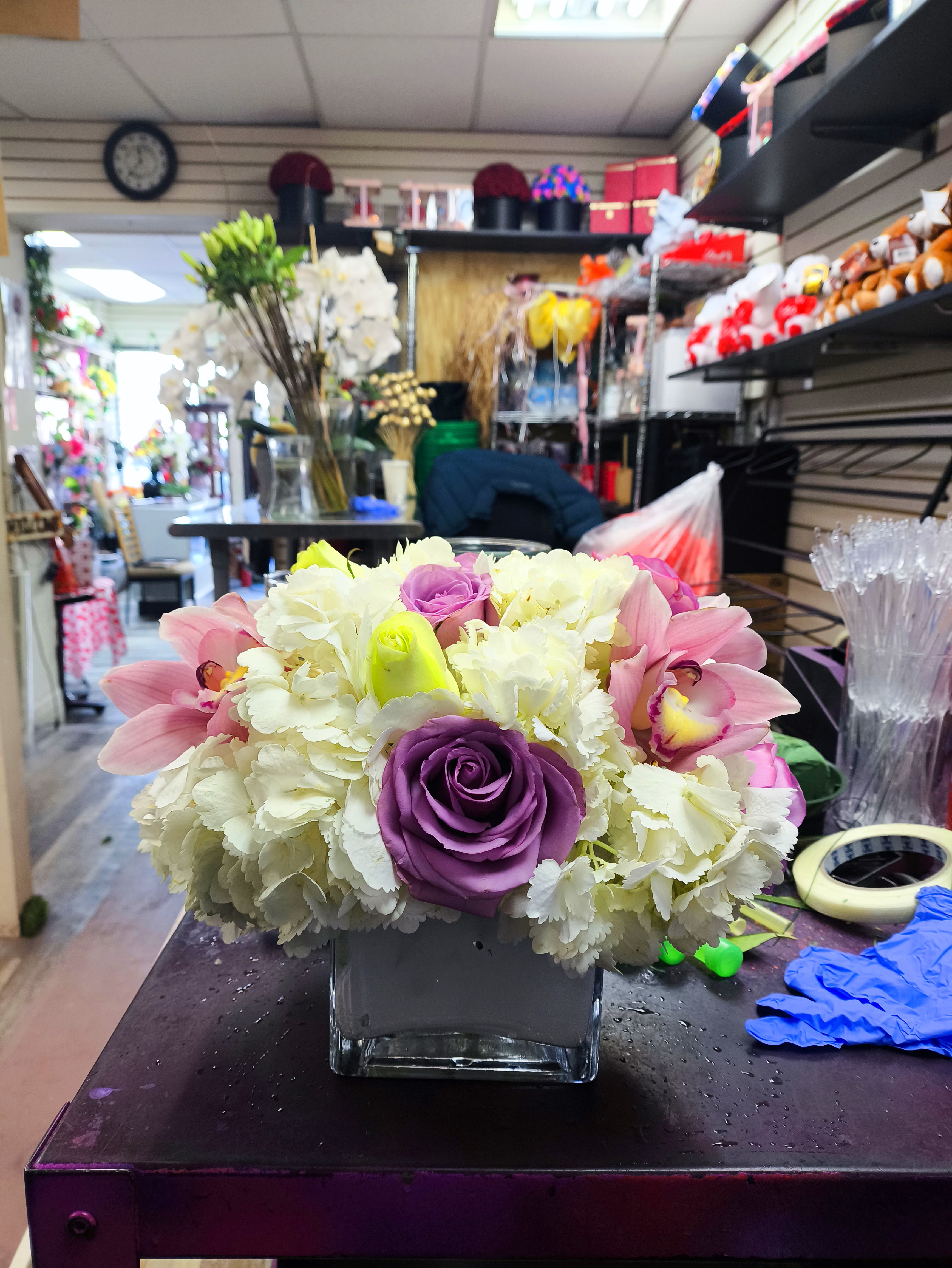 Pop of Lavender - Our most popular arrangement! Pop of Lavender  is the perfect gift to wish someone a happy birthday or to say thank you.   Arrangement Details: Includes white cymbidium orchids, lavender roses, and white hydrangea.  APPROXIMATE DIMENSIONS:10" H X 11" W X 11"L