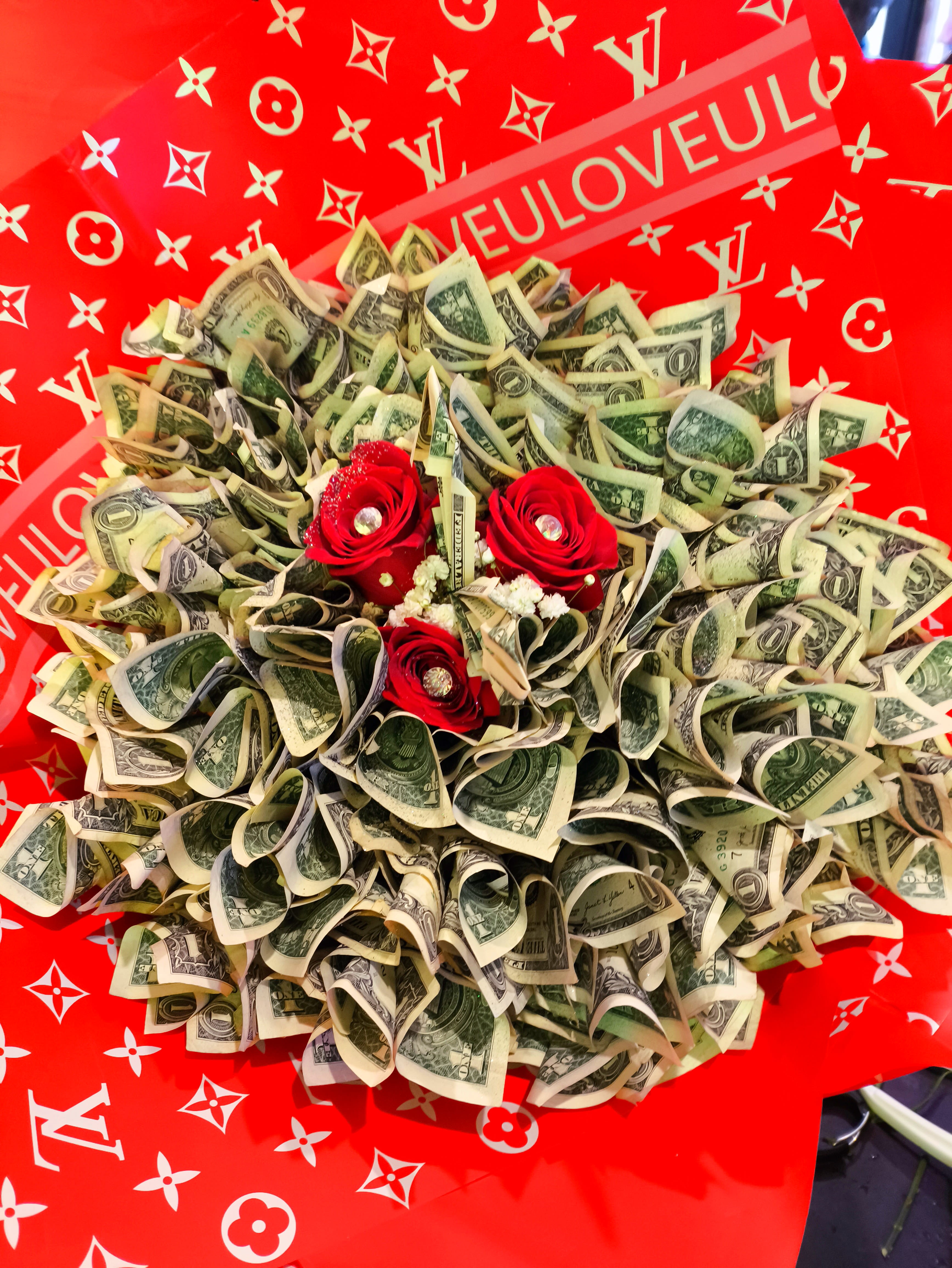 Bouquet of folded dollar bills with red roses on a red patterned background