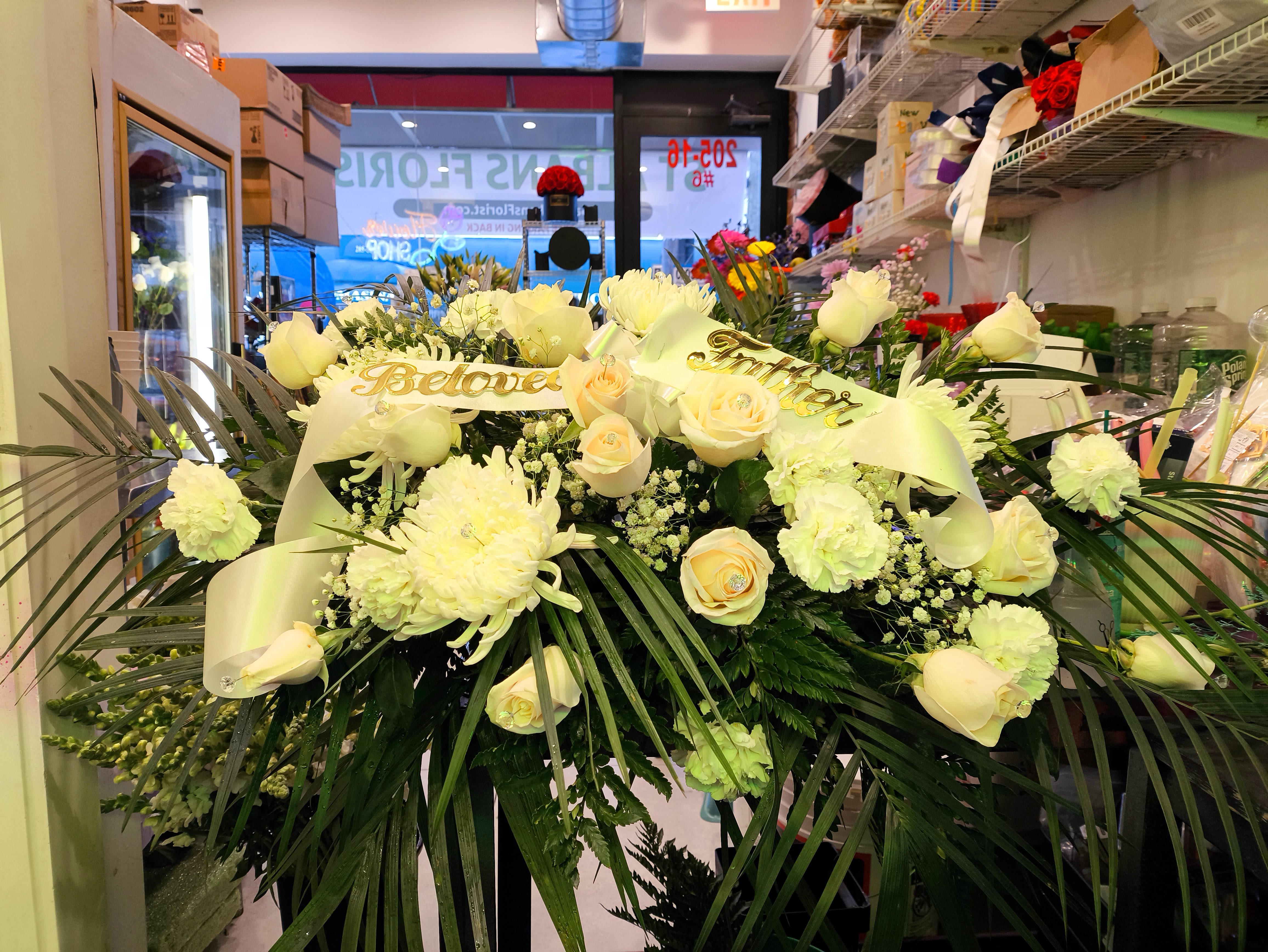 Large white floral spray with roses and ribbon in a shop