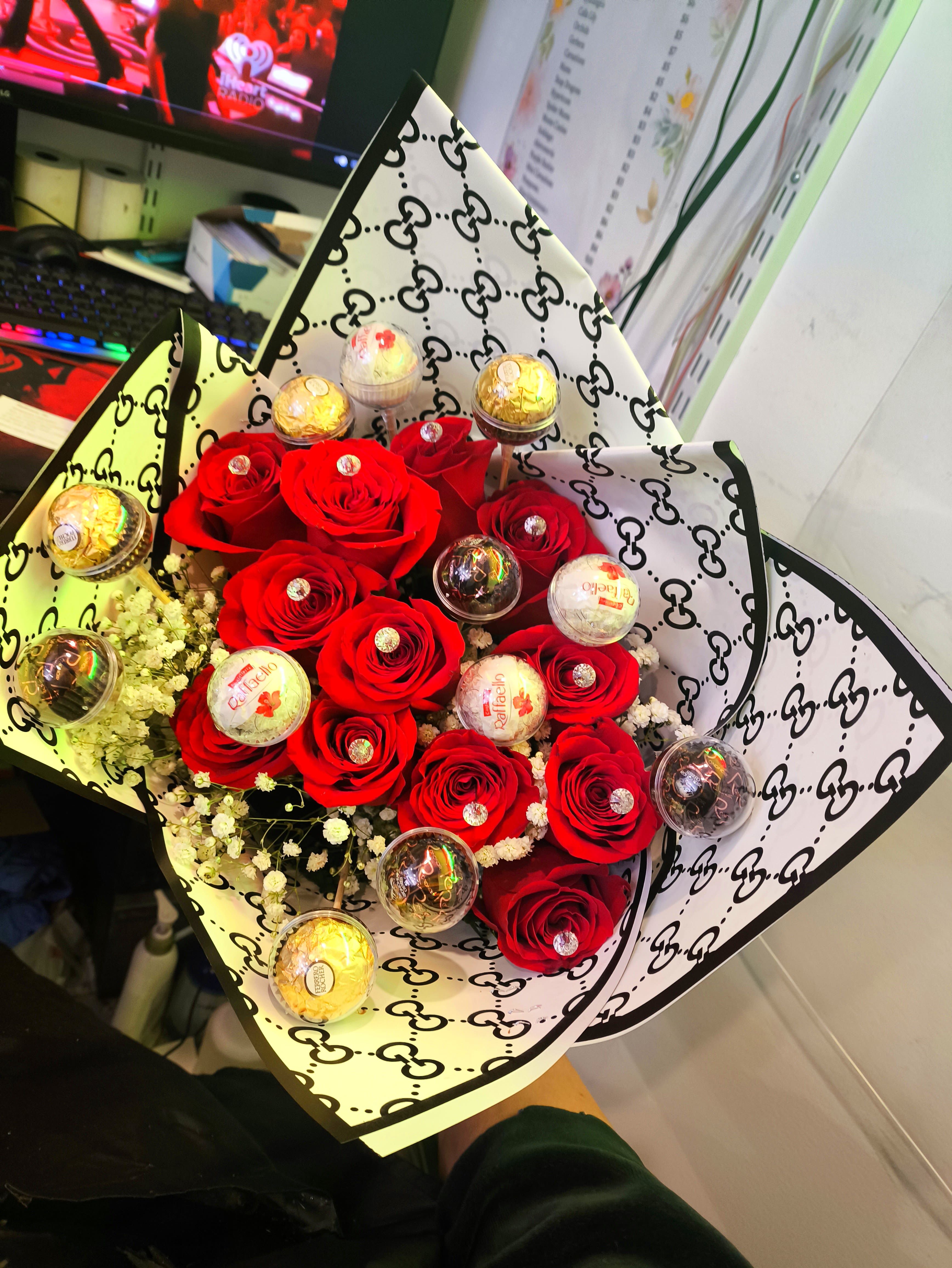 Bouquet of red roses with small wrapped chocolates in patterned paper
