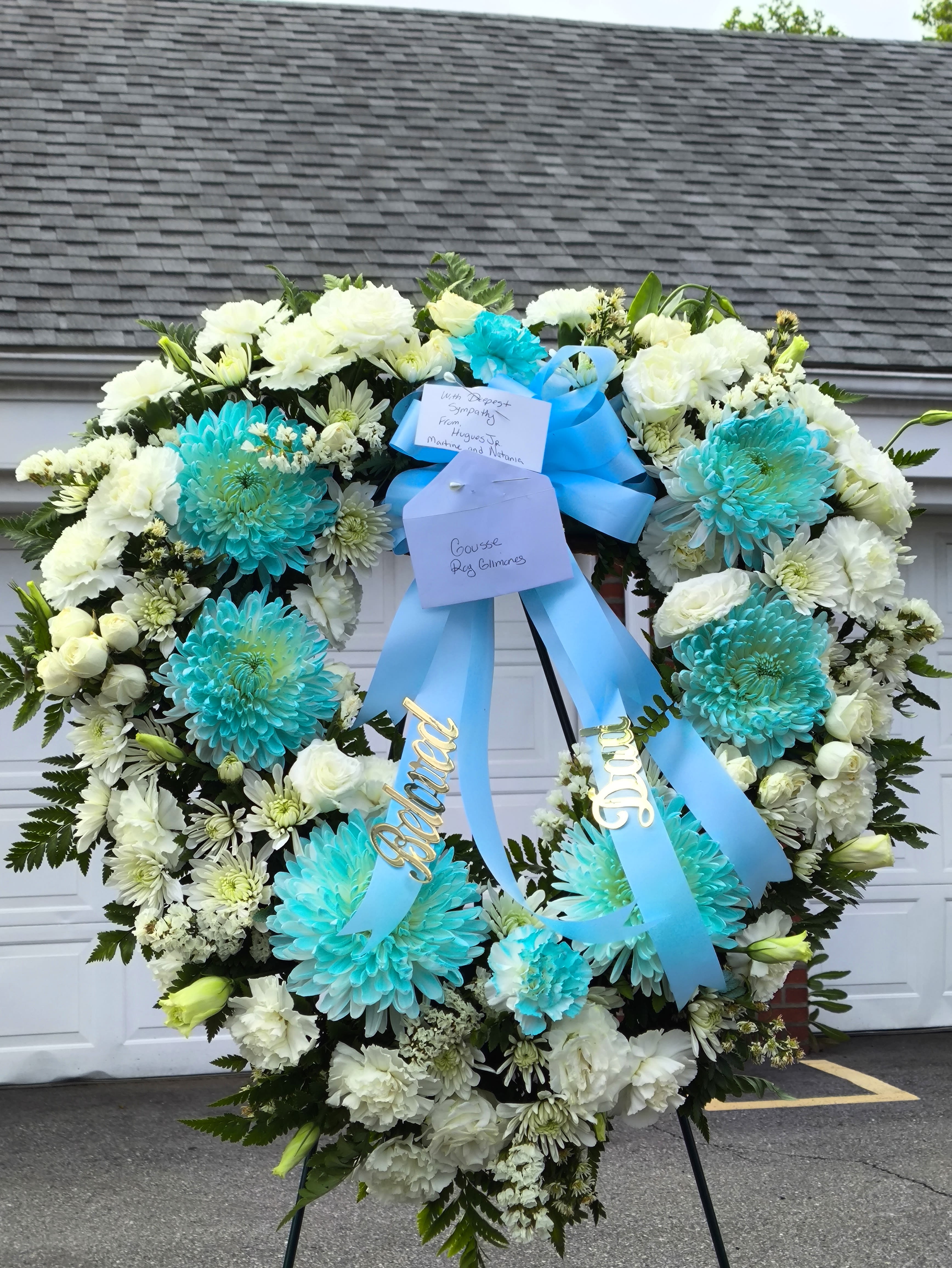 Large white and turquoise funeral wreath with blue ribbons