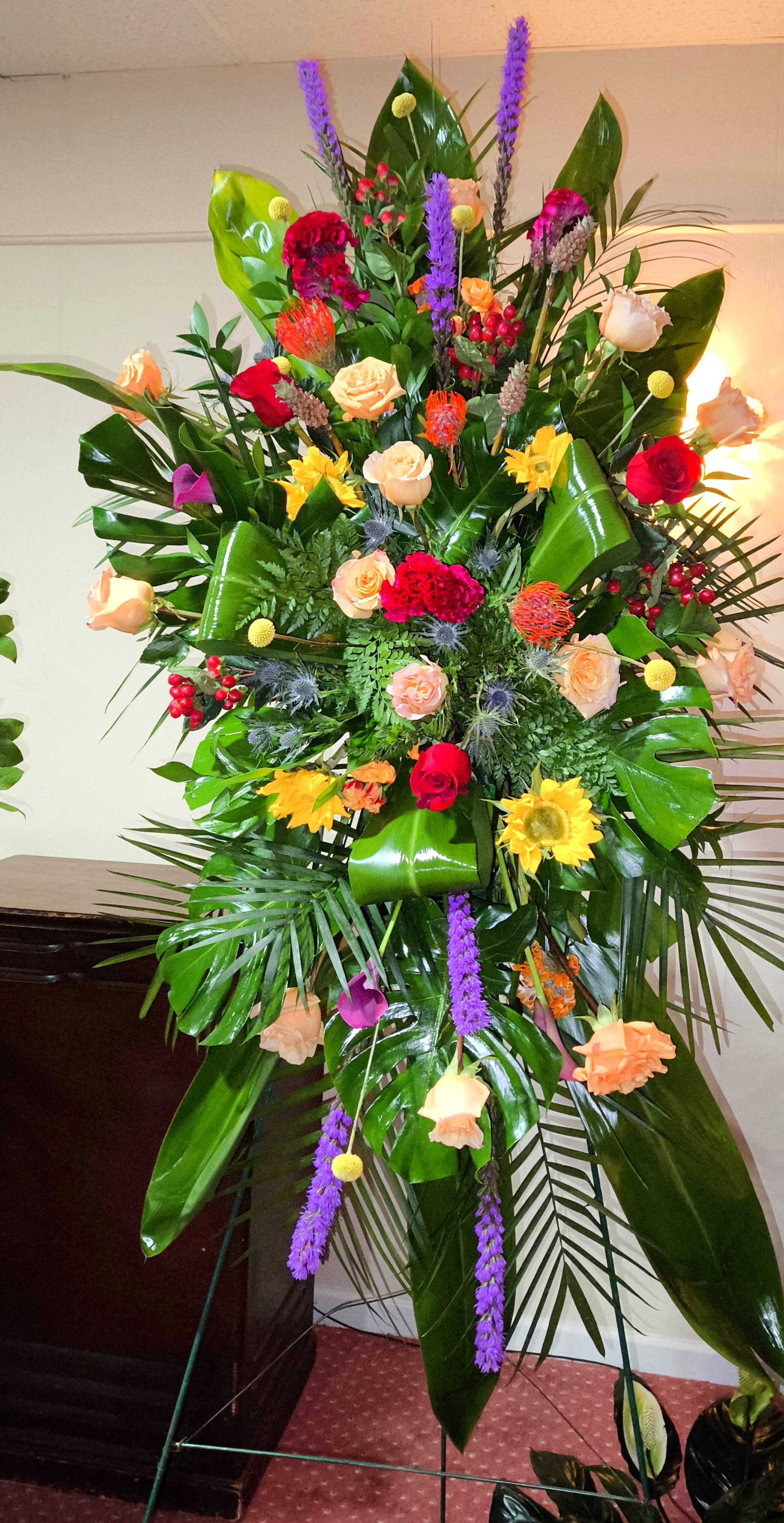 Tall standing floral spray with roses and bright mixed blooms