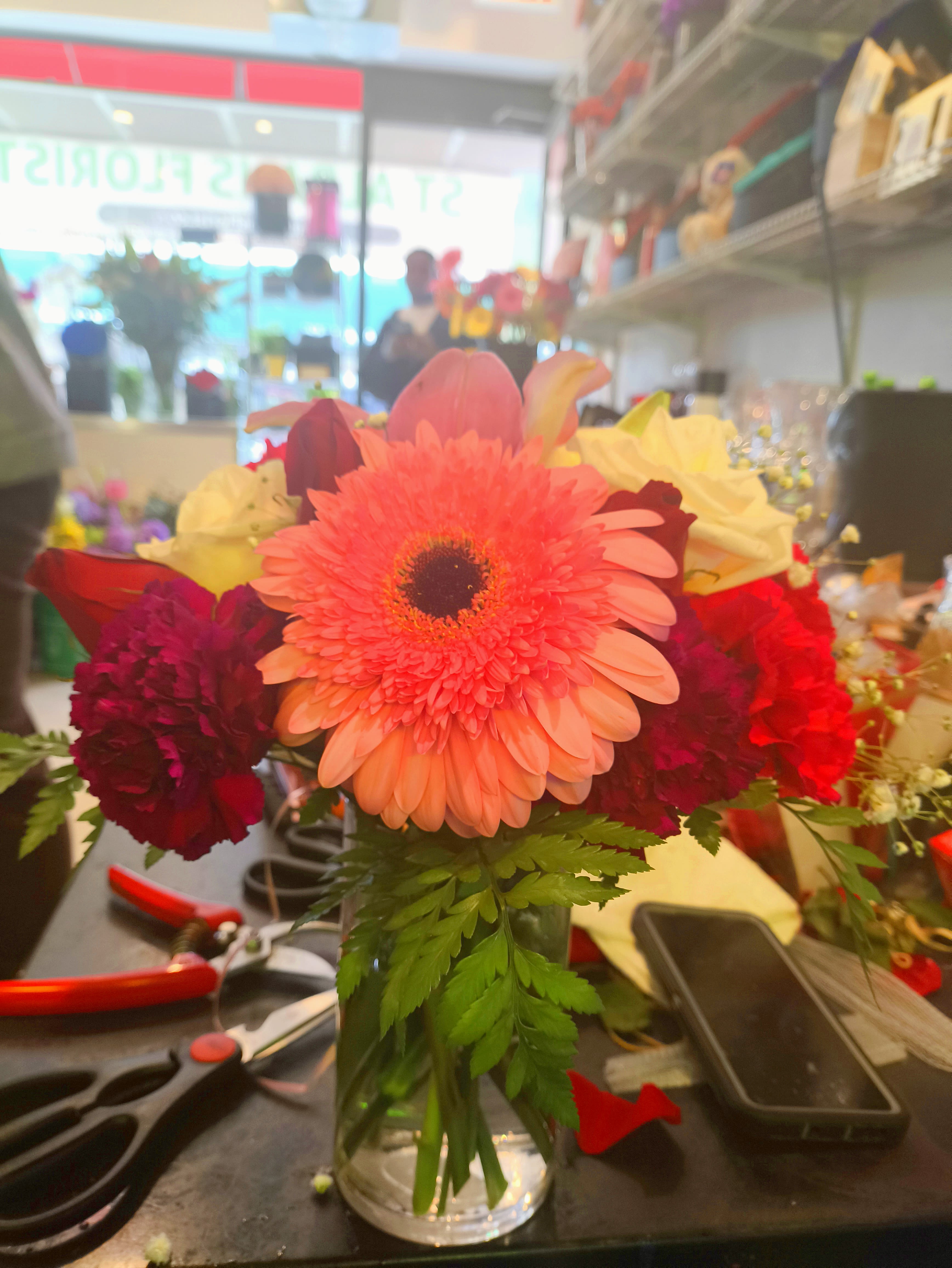 Bright mixed bouquet with a pink gerbera daisy in a glass vase