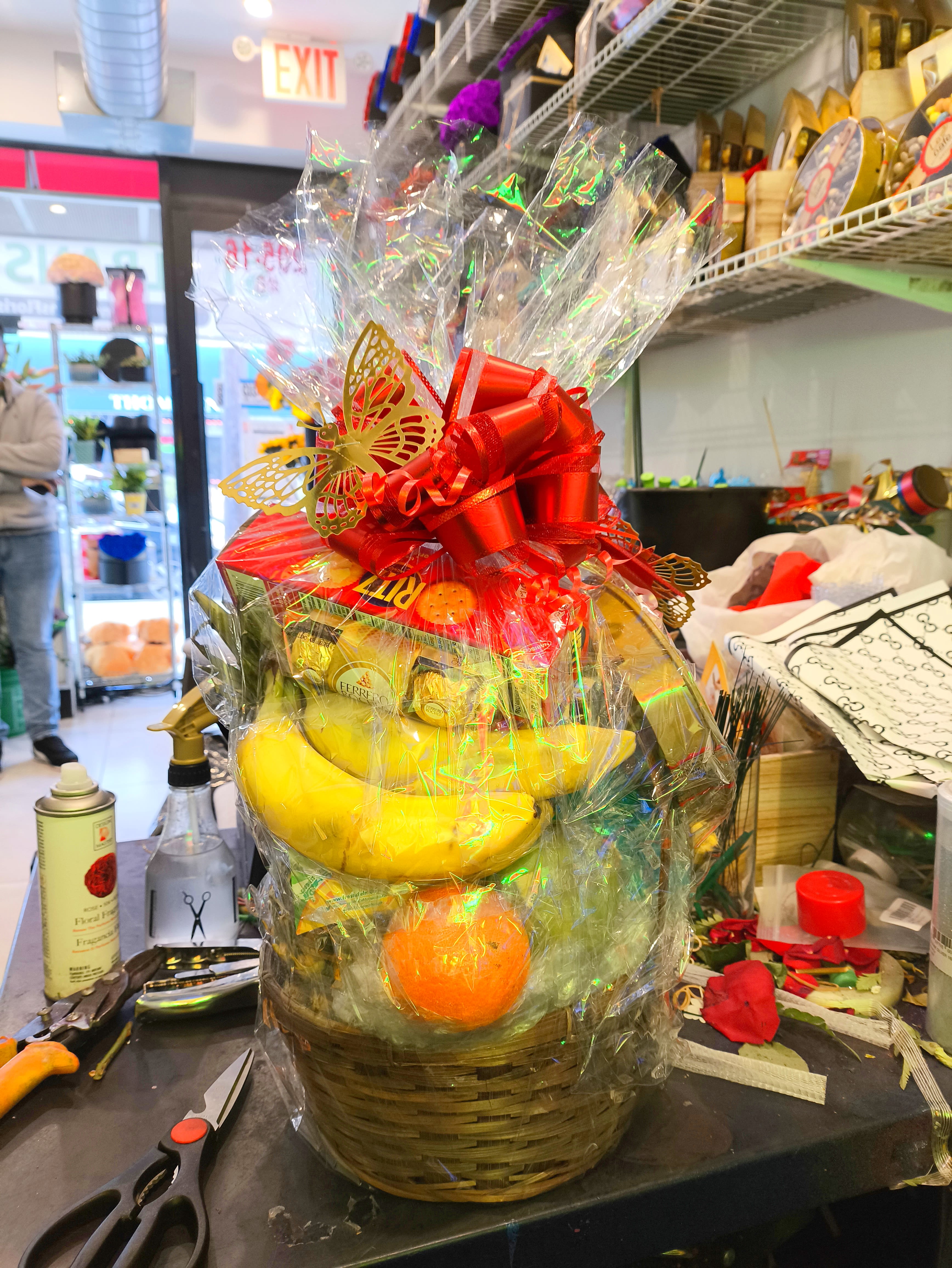 Gift basket with bananas, oranges, and chocolates wrapped in clear cellophane