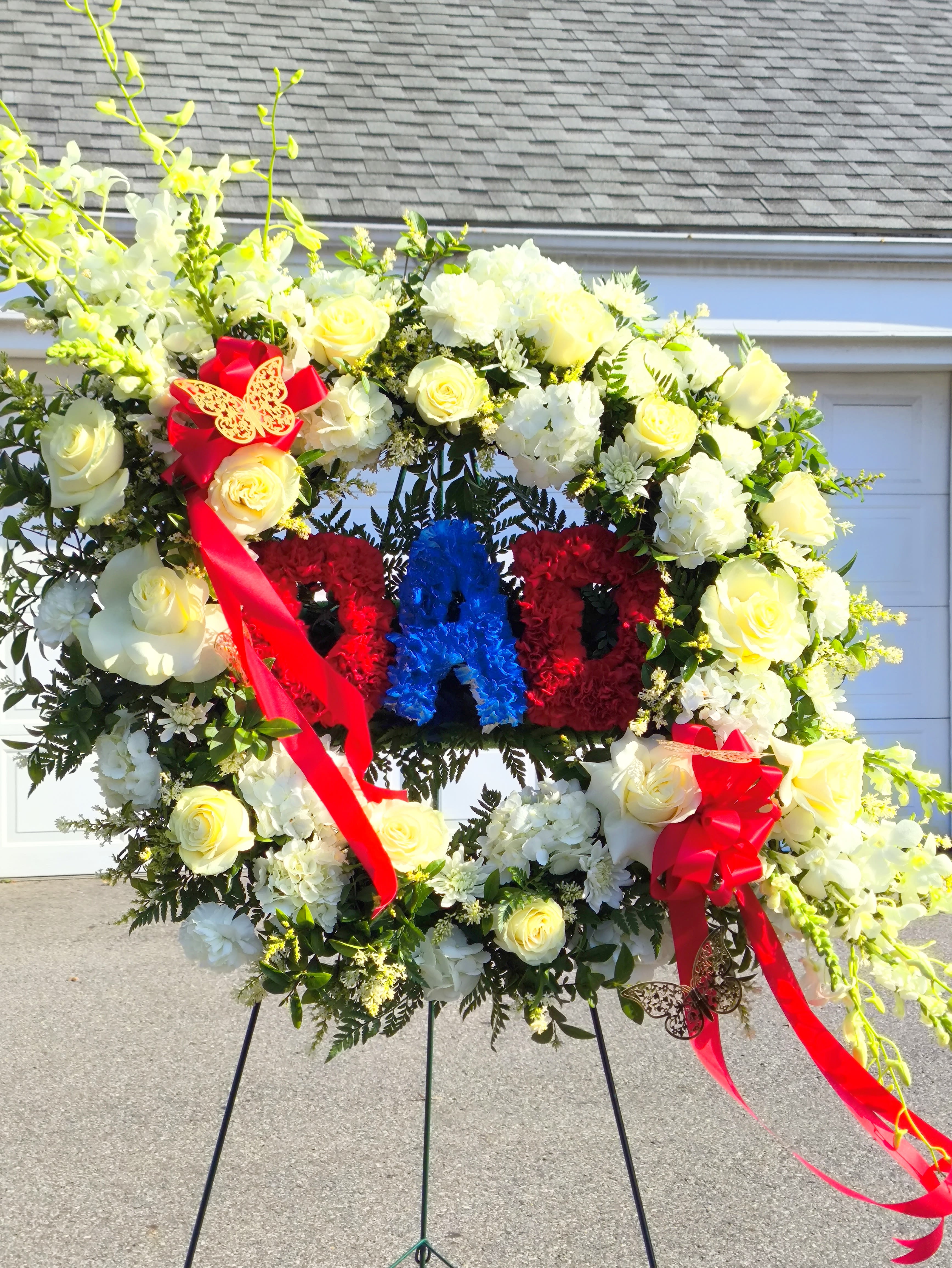 Large floral wreath on an easel with red, white, and blue lettering