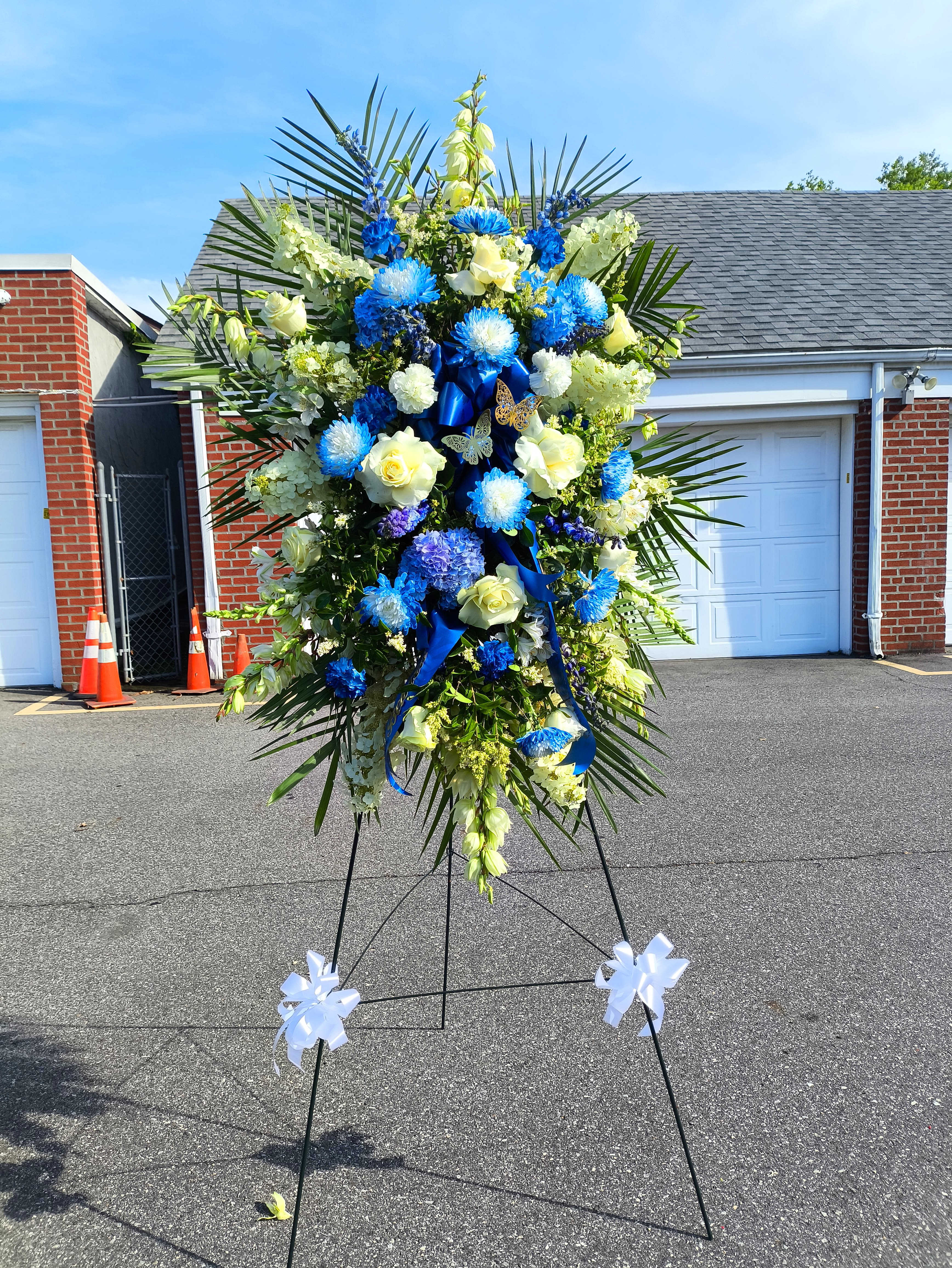 Large standing floral spray with blue and white flowers on an easel