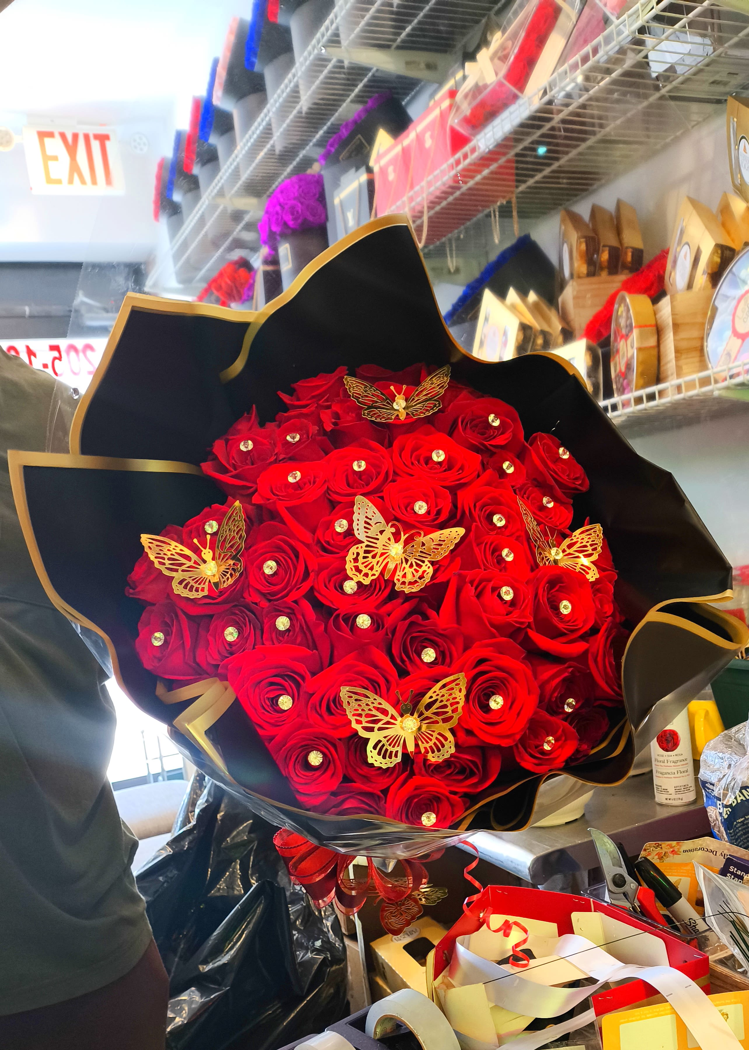 Bouquet of red roses with gold butterfly decorations in black wrap