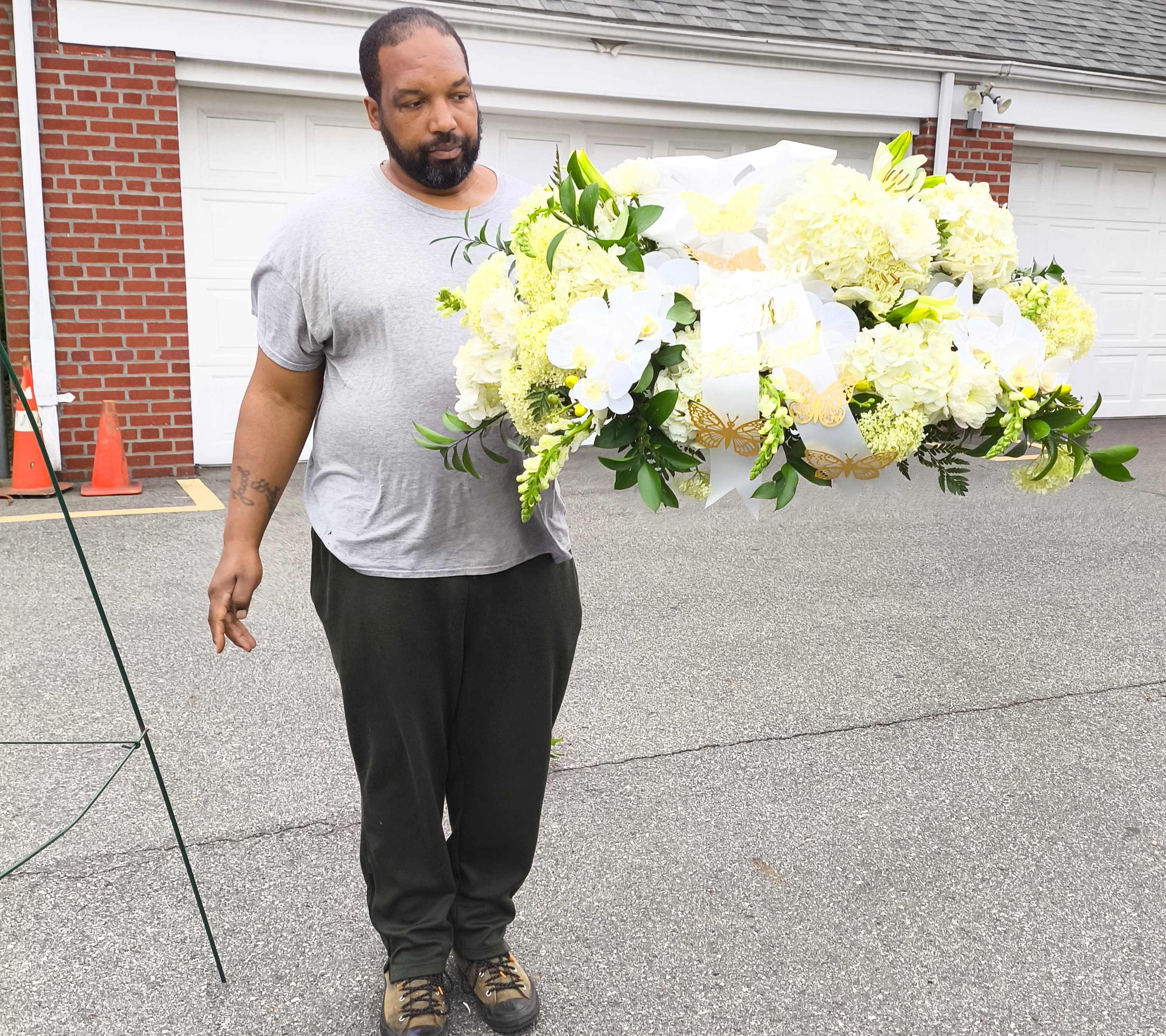 Man holding a large white floral spray with ribbons and butterflies