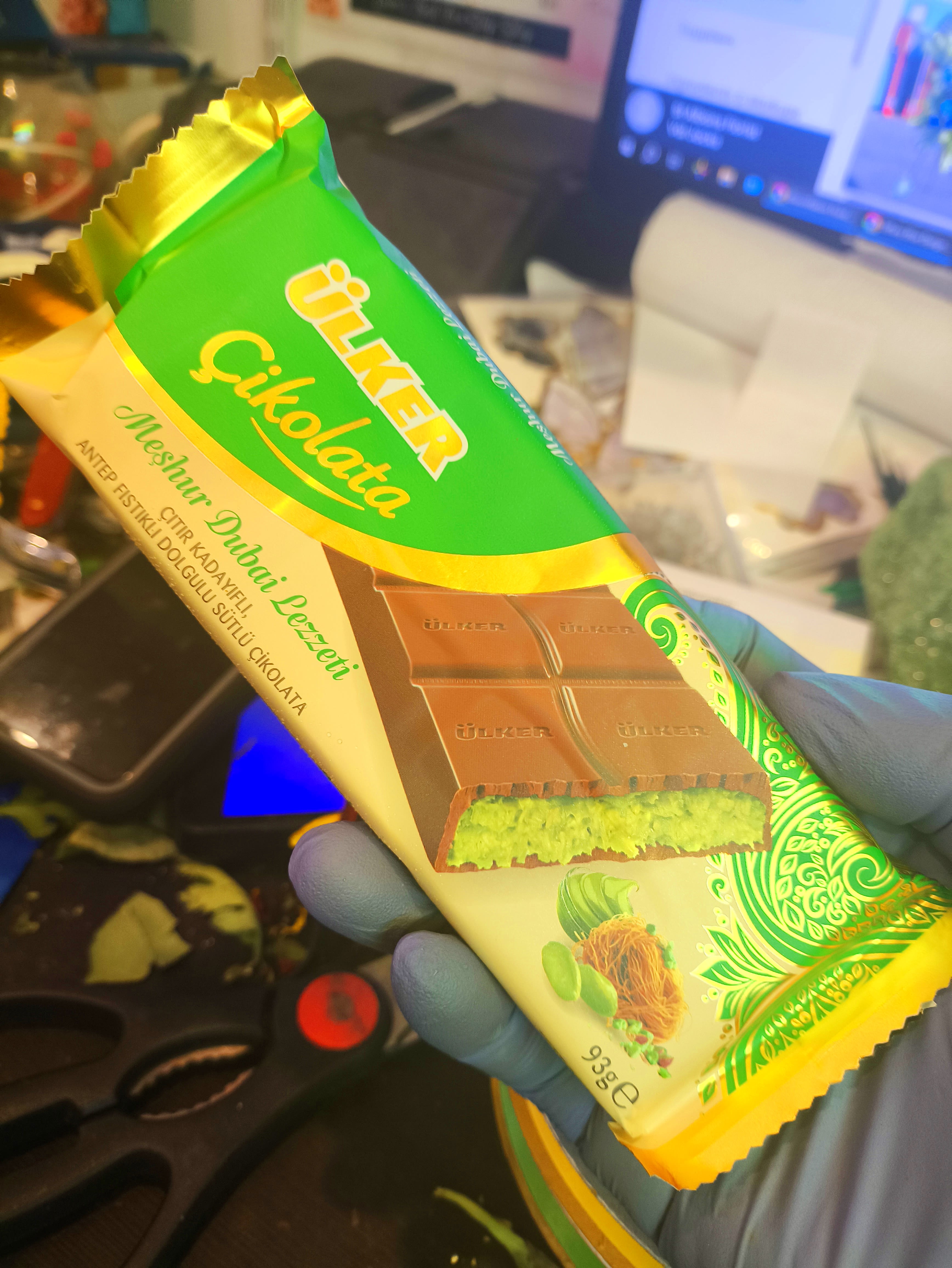 Hand holding a wrapped chocolate bar with green and gold packaging