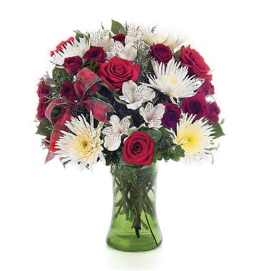 Red roses and white daisies in a green glass vase with a plaid ribbon