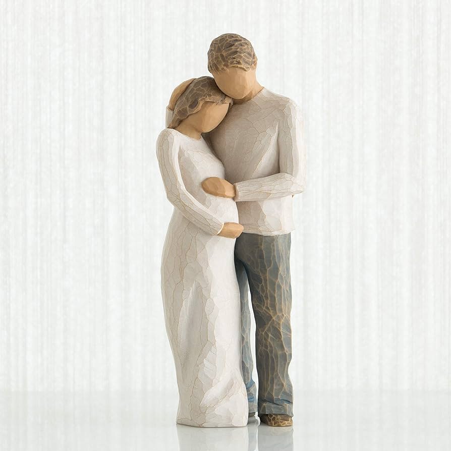 Two carved figurines embracing, one in a white dress and one in gray pants