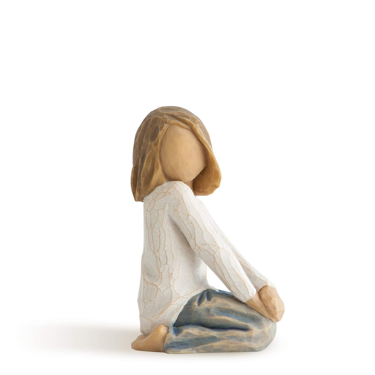 Carved figurine of a seated girl in a white top and blue pants, shown in side profile.