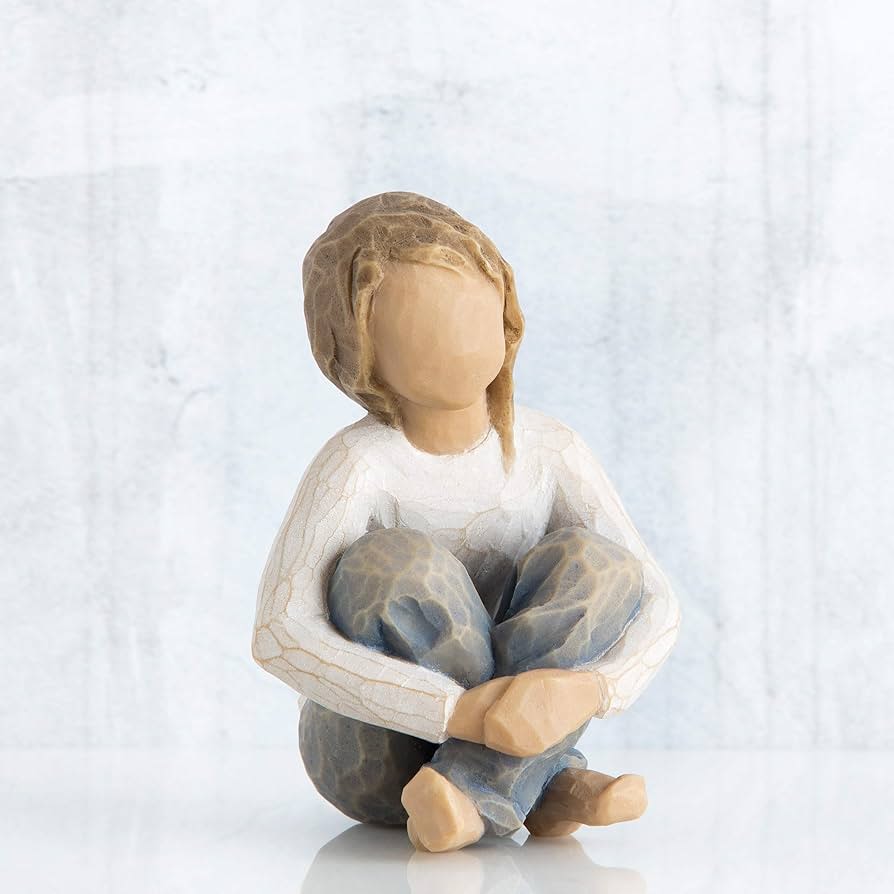 Wooden figurine of a seated child with knees hugged to chest