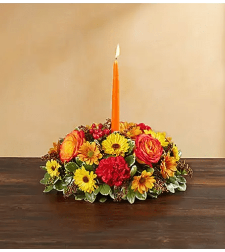 Low floral centerpiece with an orange candle in the middle