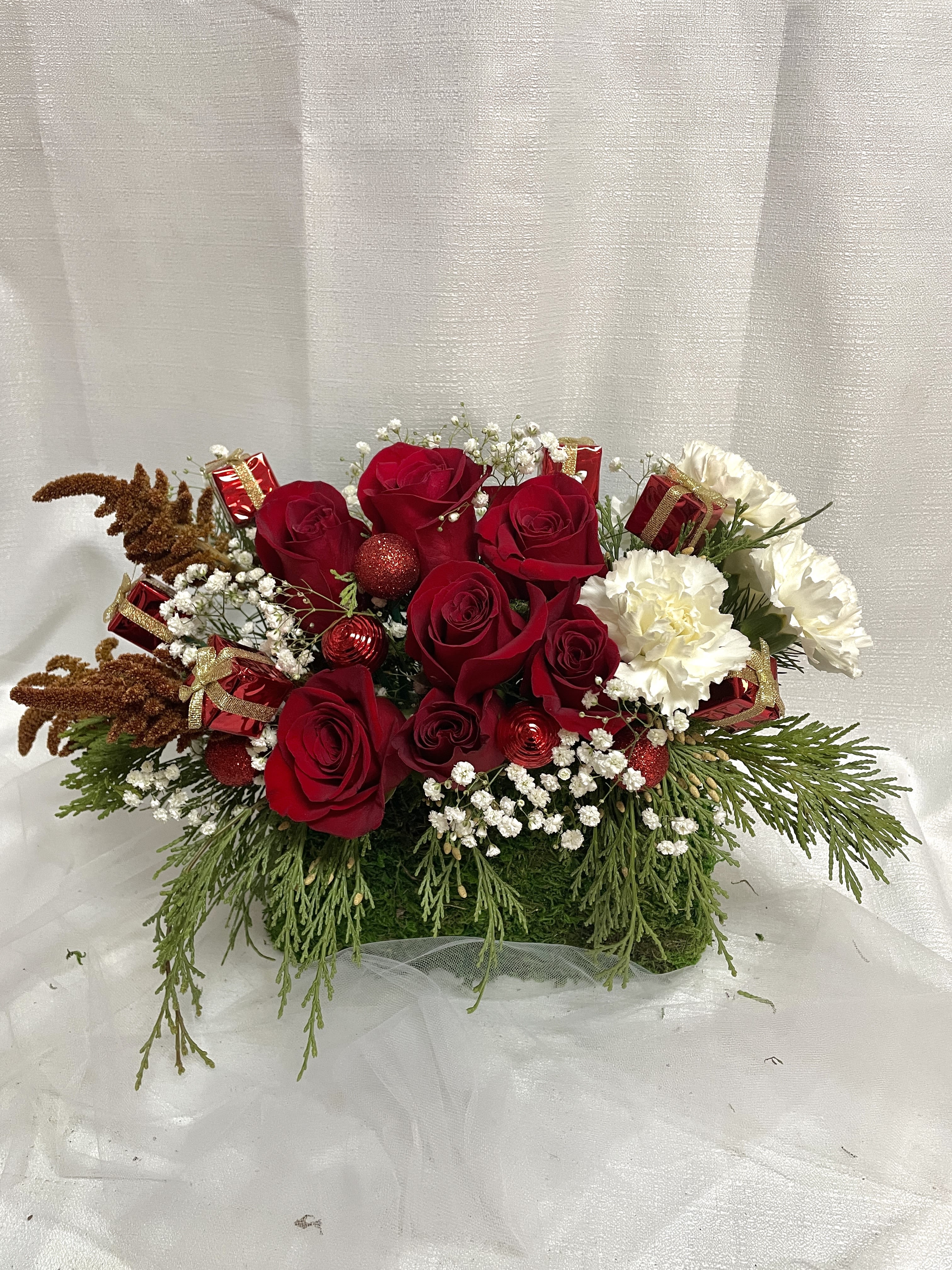 Jingle Bell Blooms - An enchanting holiday arrangement set in a lovely green moss purse (with handles). Ring in this holiday season with a gorgeous array of red roses, babies breath, and white carnations.