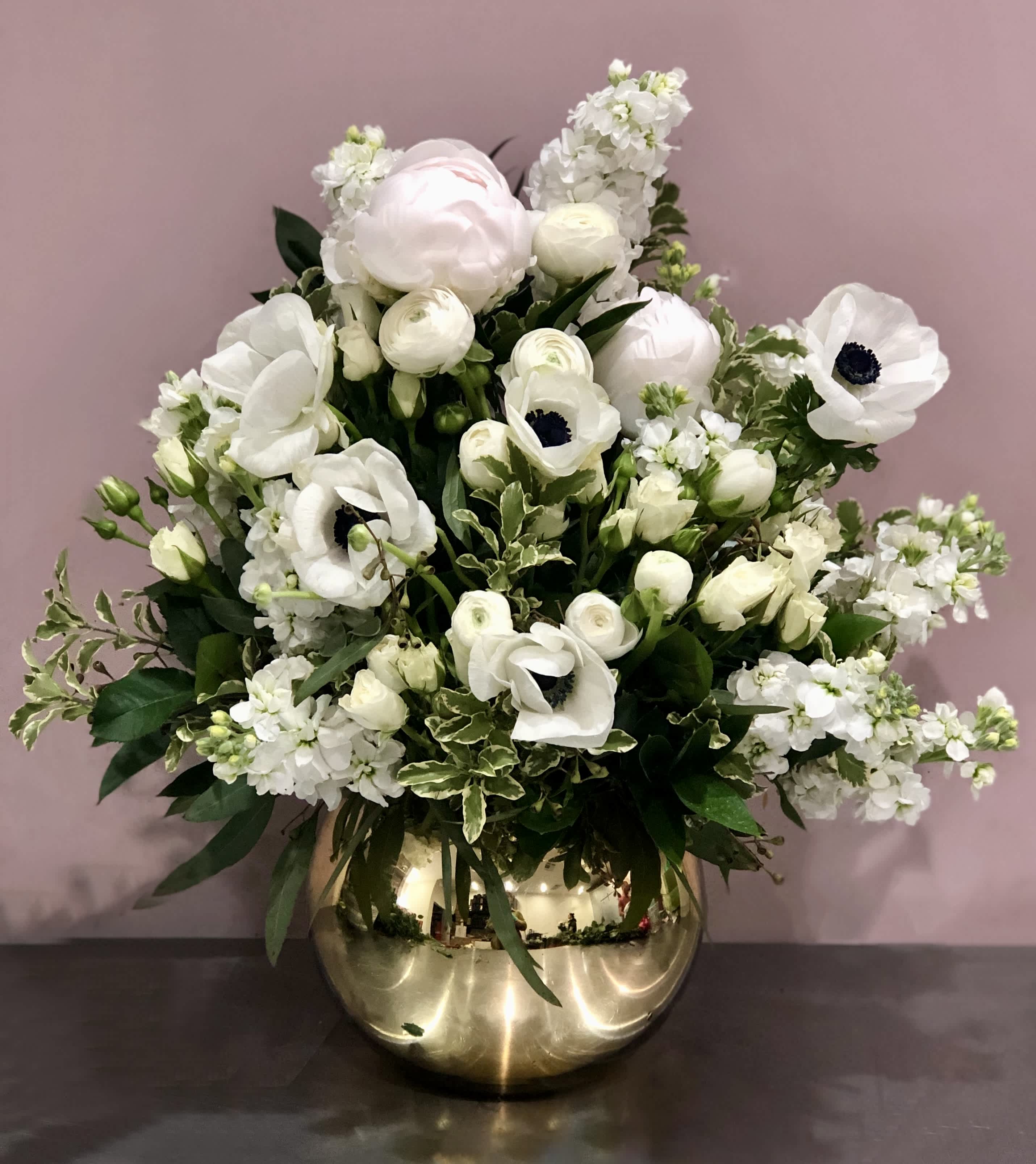 White floral arrangement in a gold vase with anemones and ranunculus