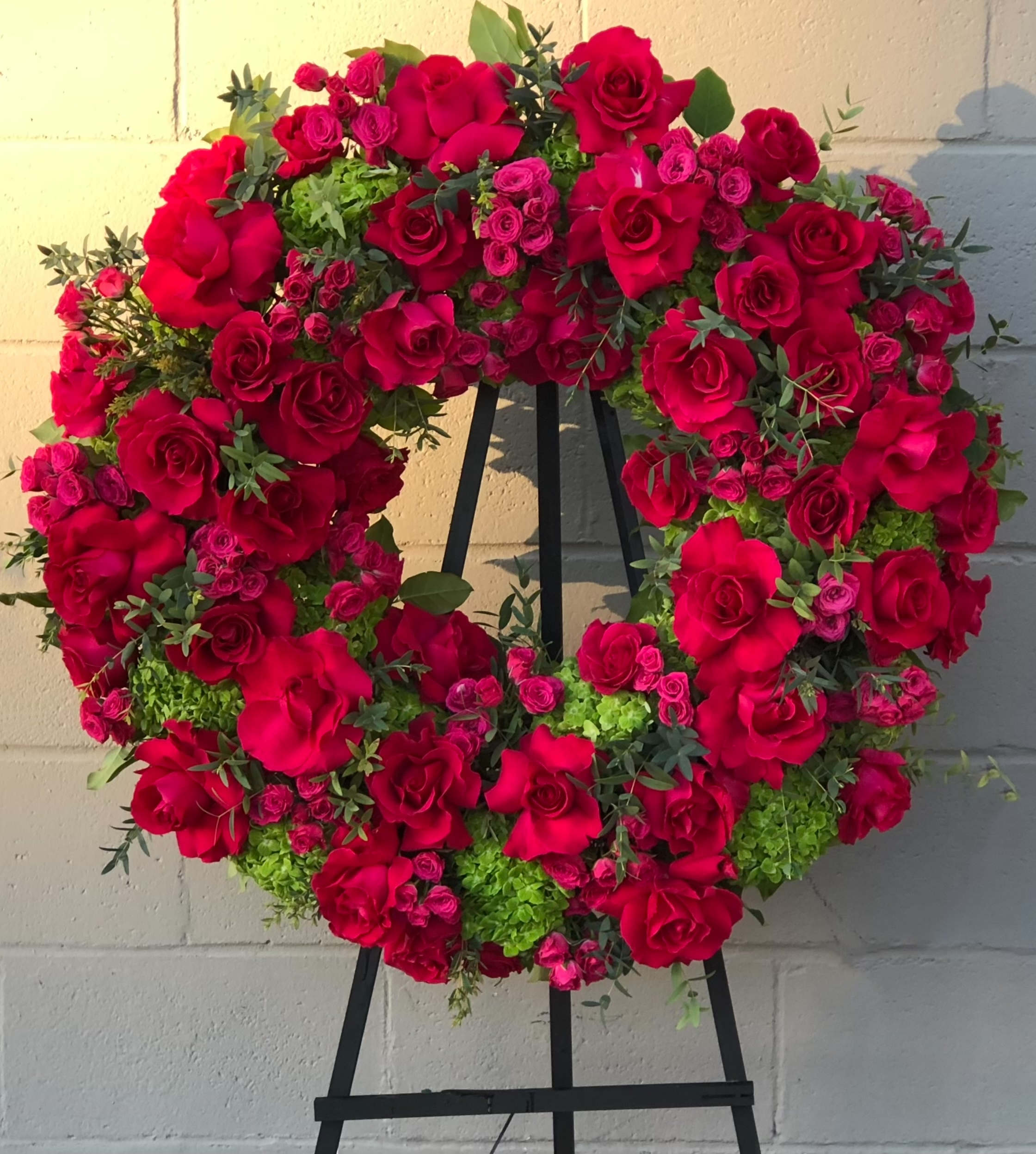Heart-shaped wreath of red roses and pink spray roses on an easel