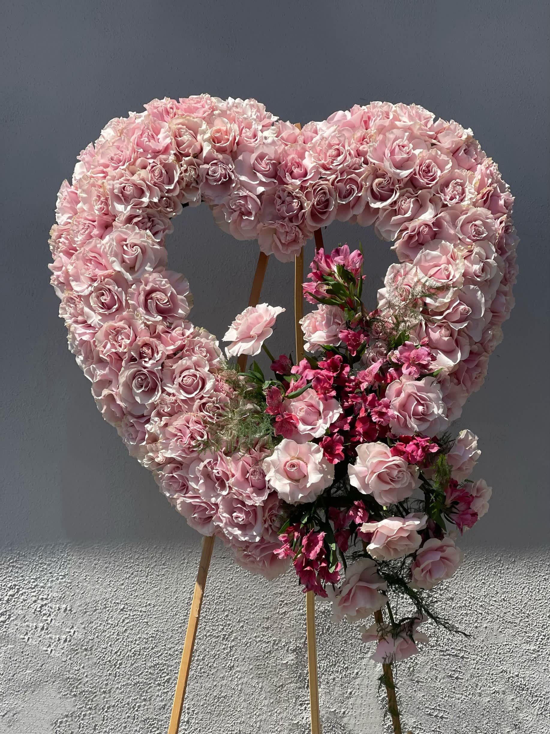 Heart-shaped pink rose floral display on an easel