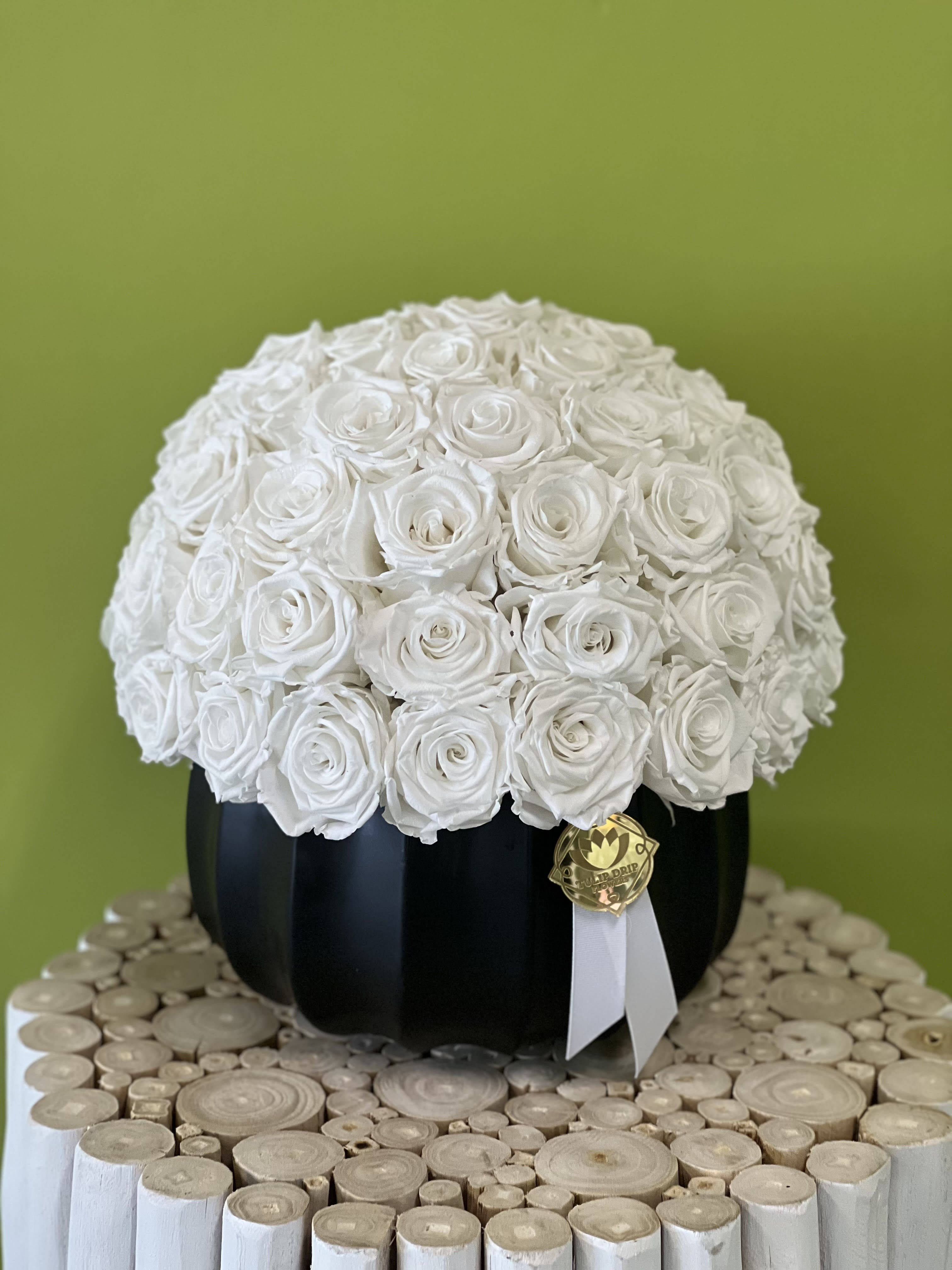 White rose arrangement in a black round box with a ribbon tag