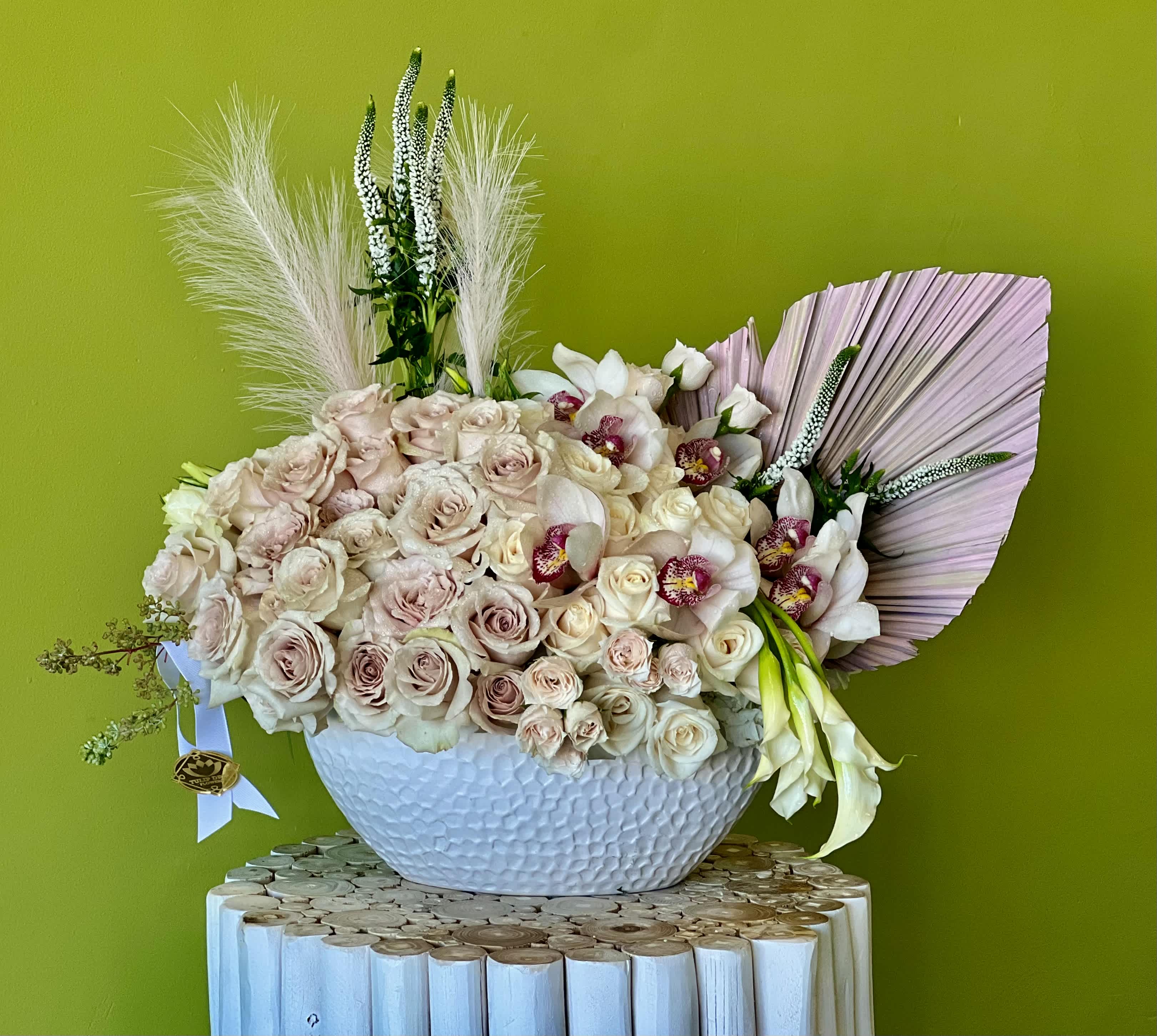 Large bouquet of pale roses and white orchids in a white bowl vase