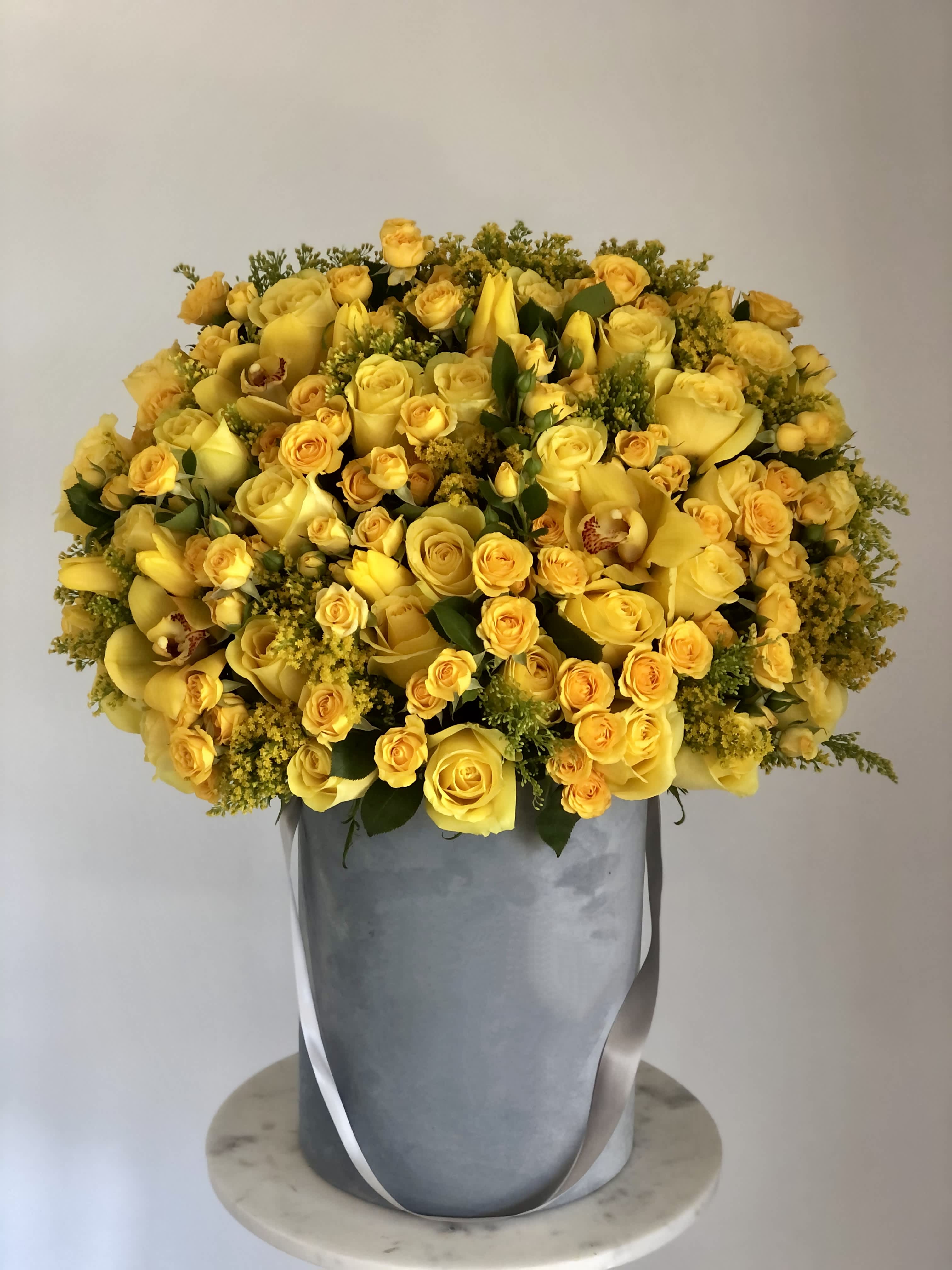 Lemon sorbet  - Yellow roses, yellow Spray roses, yellow Orchids in a gray velvet box .  THIS IMAGE SHOWS THE DELUXE SIZE FO THE ARRANGEMENT. 