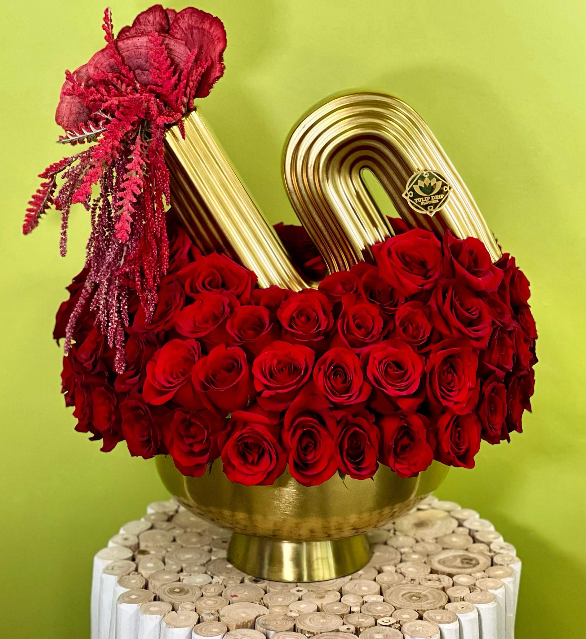 Red roses arranged in a gold vase with a gold handle accent