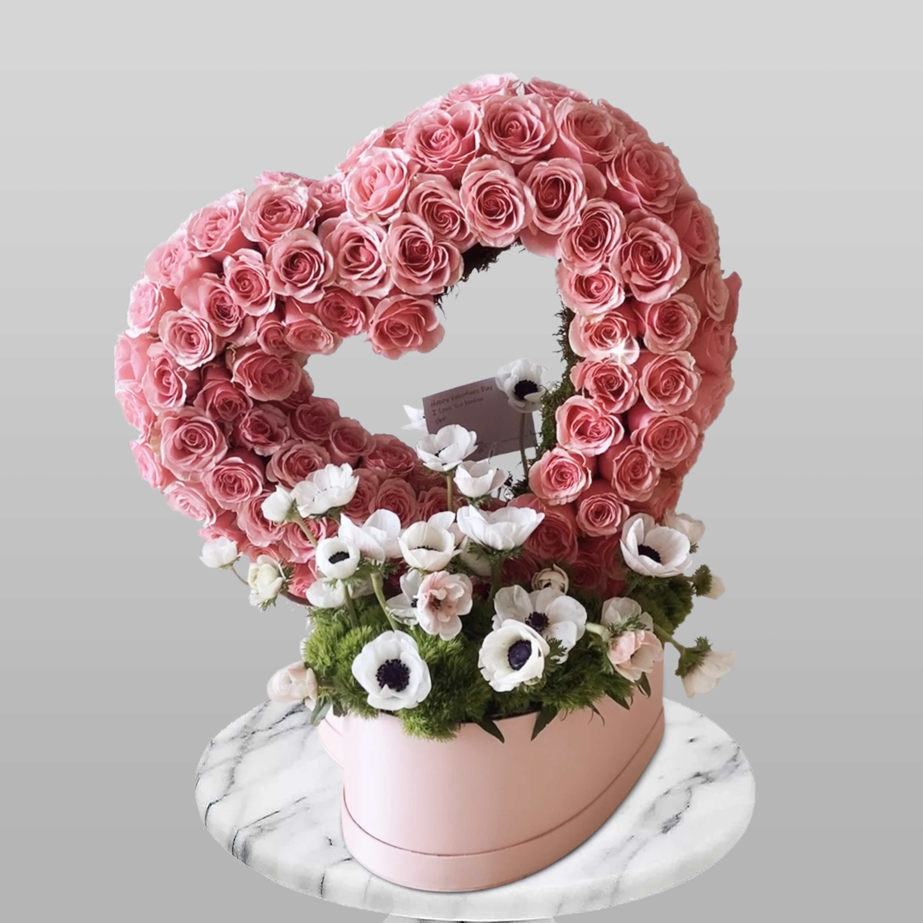 Heart-shaped pink rose arrangement with white anemones in a pink box