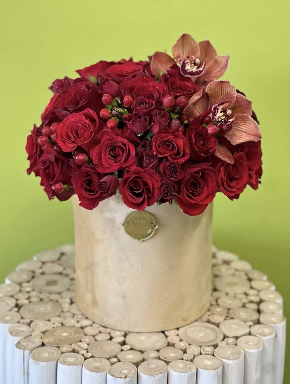 Red rose arrangement in a beige hatbox with two orchid blooms