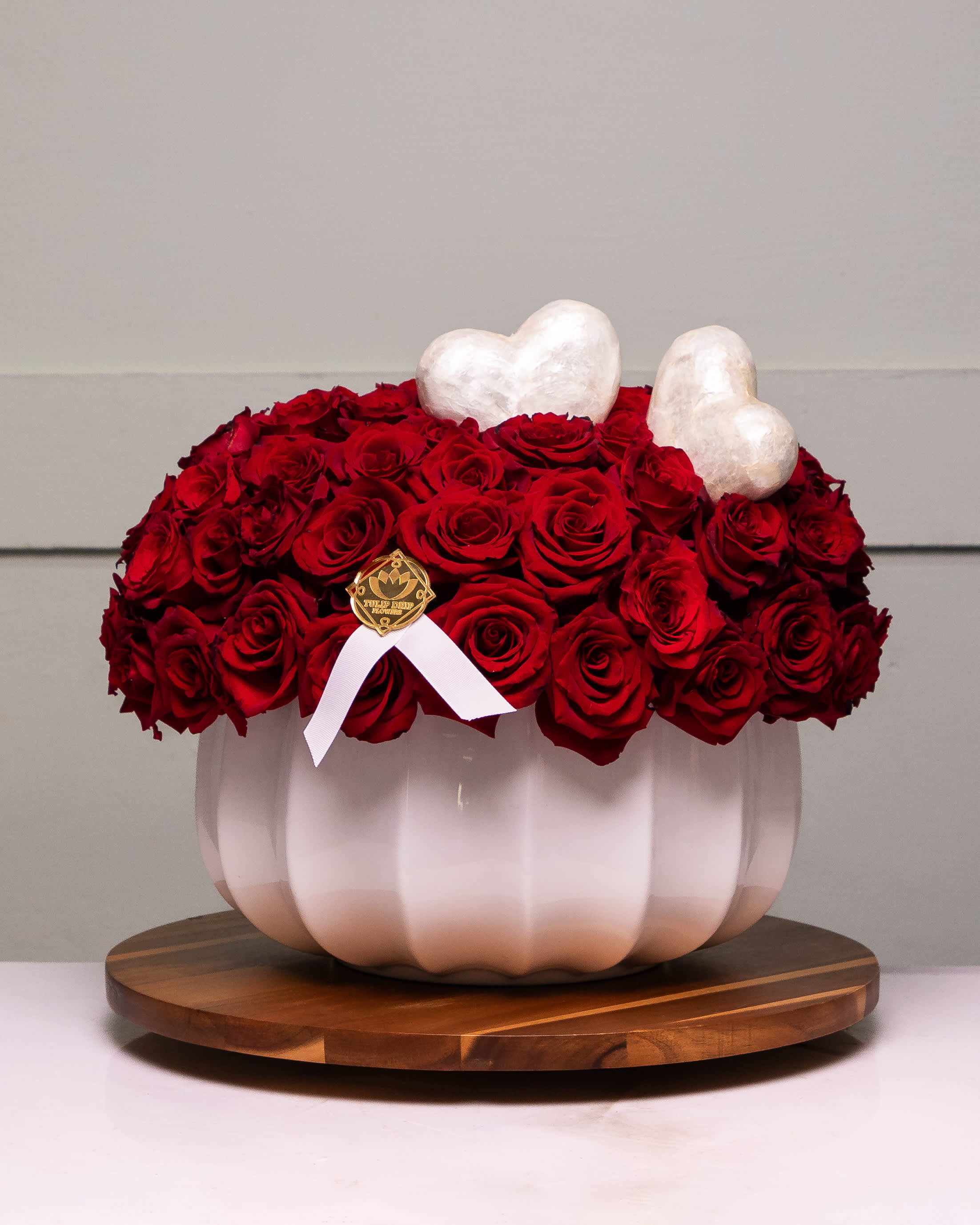 Red rose arrangement in a white pumpkin-shaped vase with heart accents