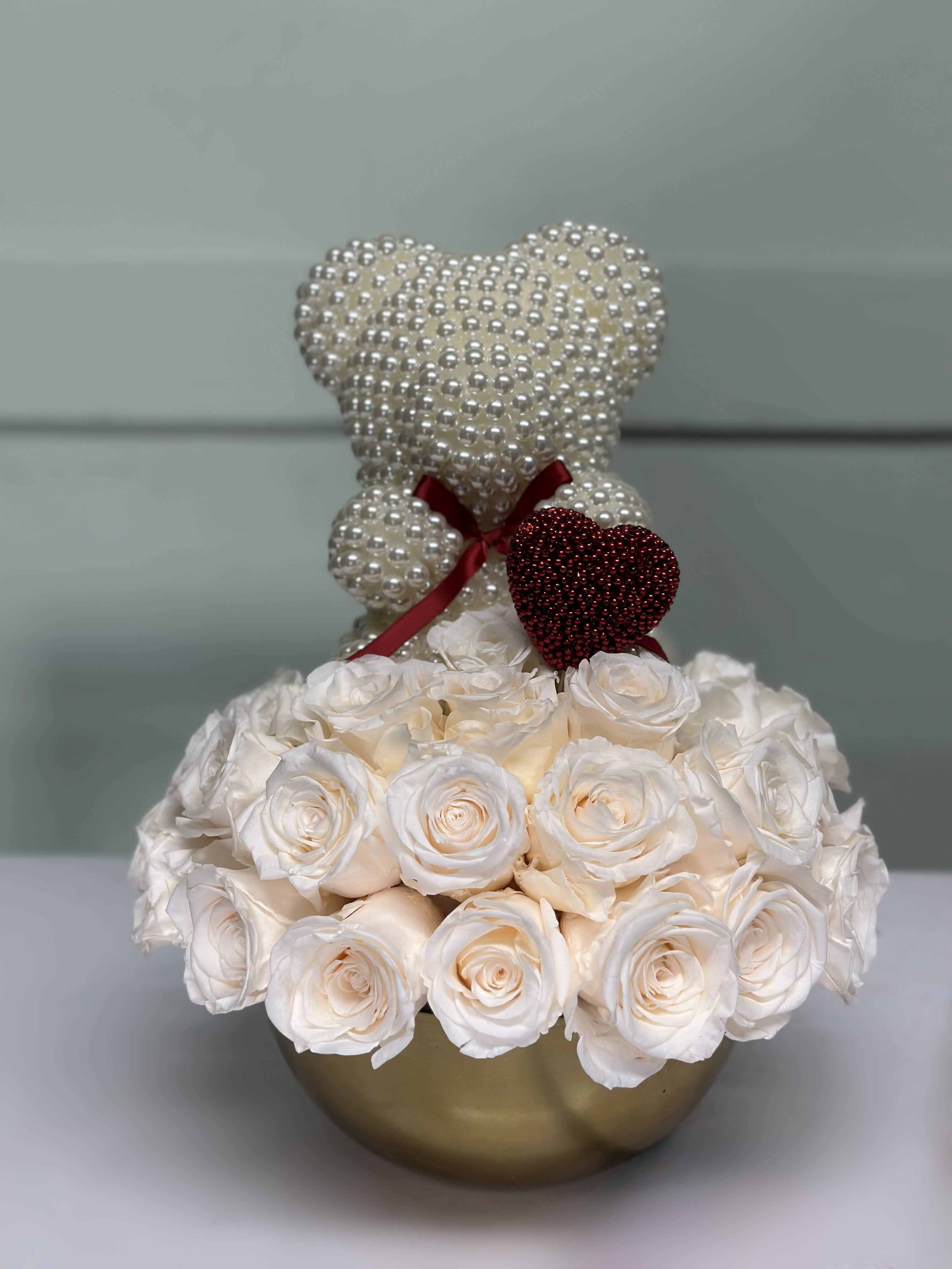 White rose arrangement with pearl teddy bears in a gold vase
