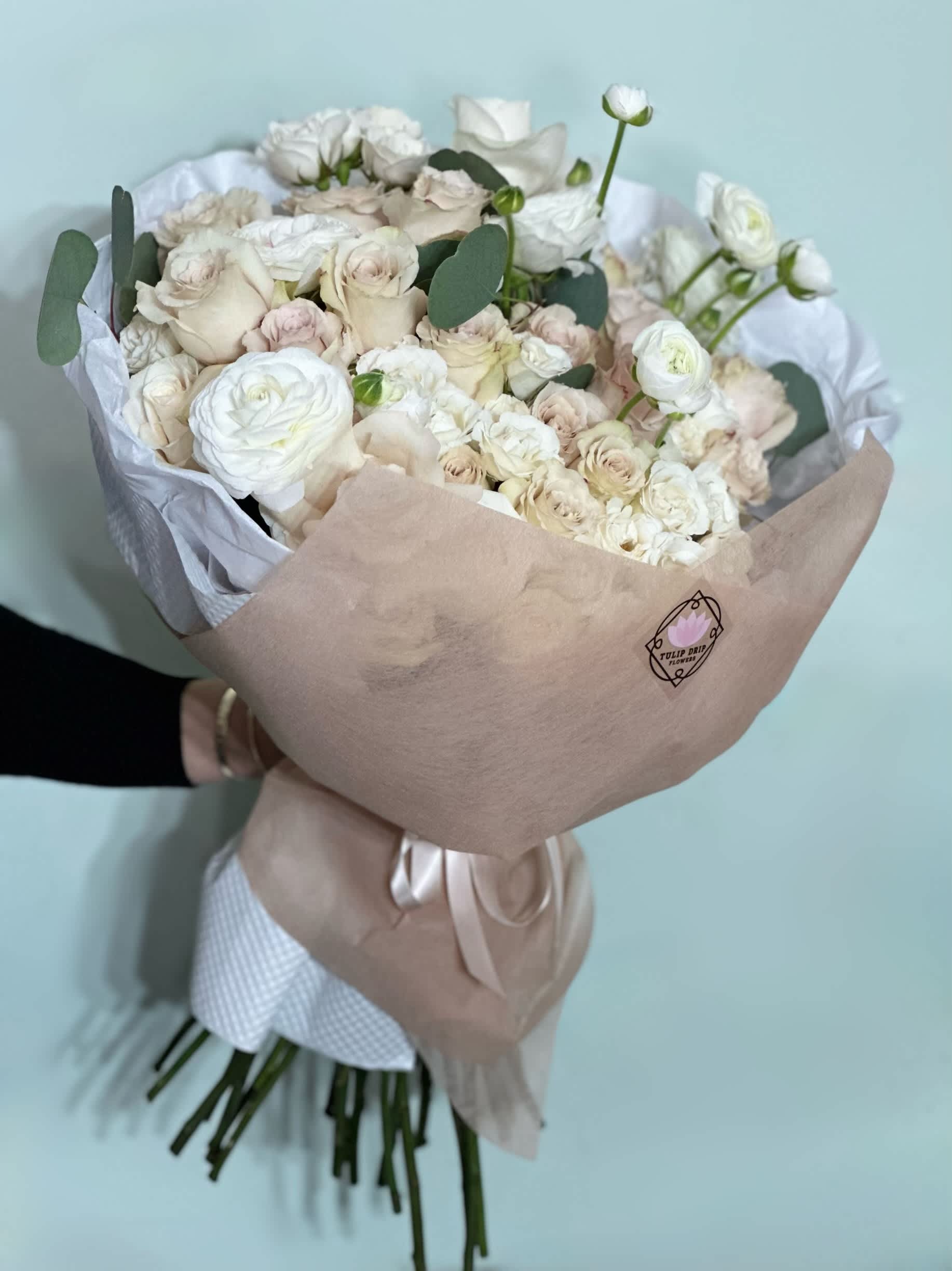 Bouquet of white and blush roses wrapped in beige paper