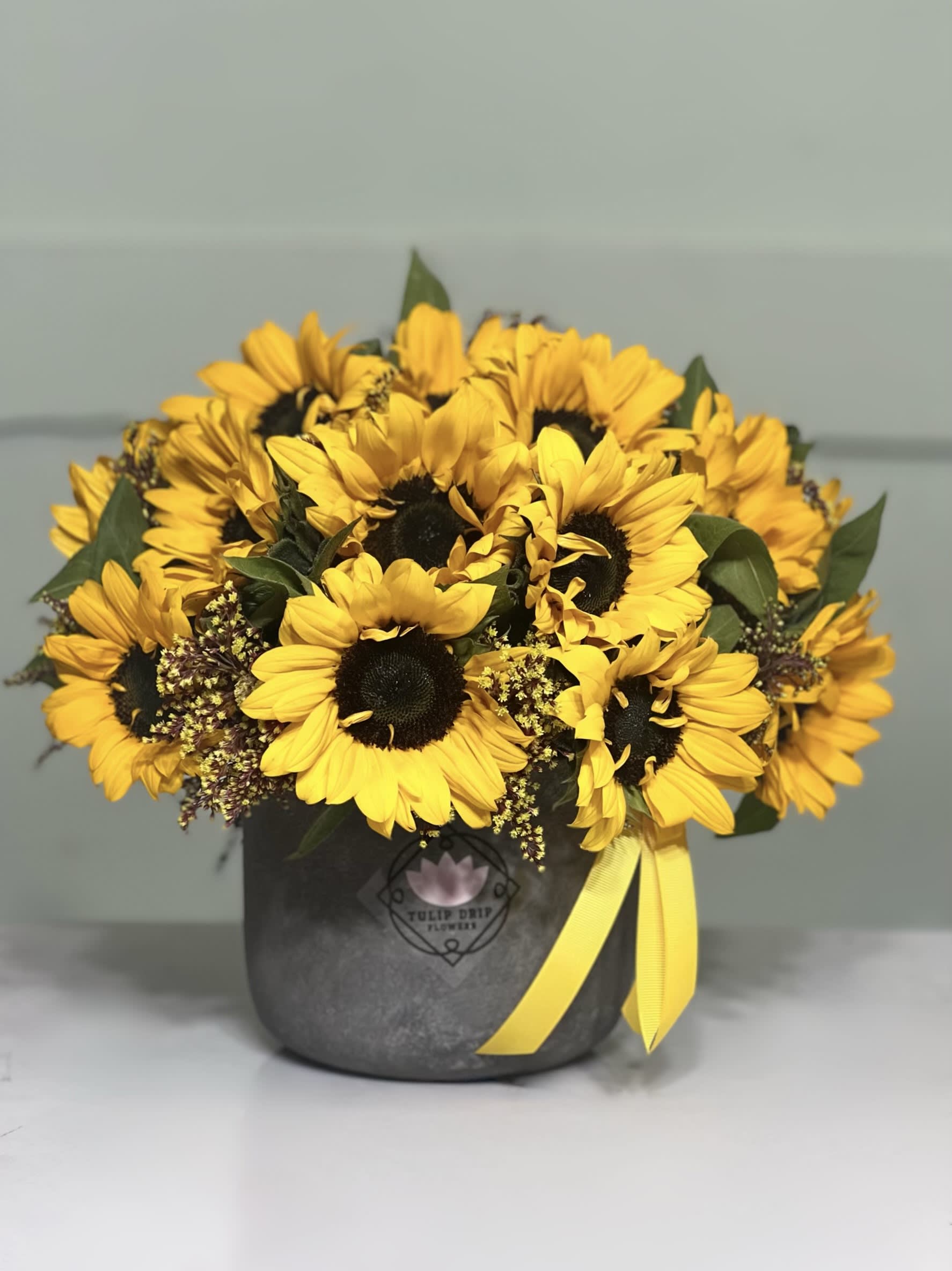 Bouquet of yellow sunflowers in a dark box with a yellow ribbon