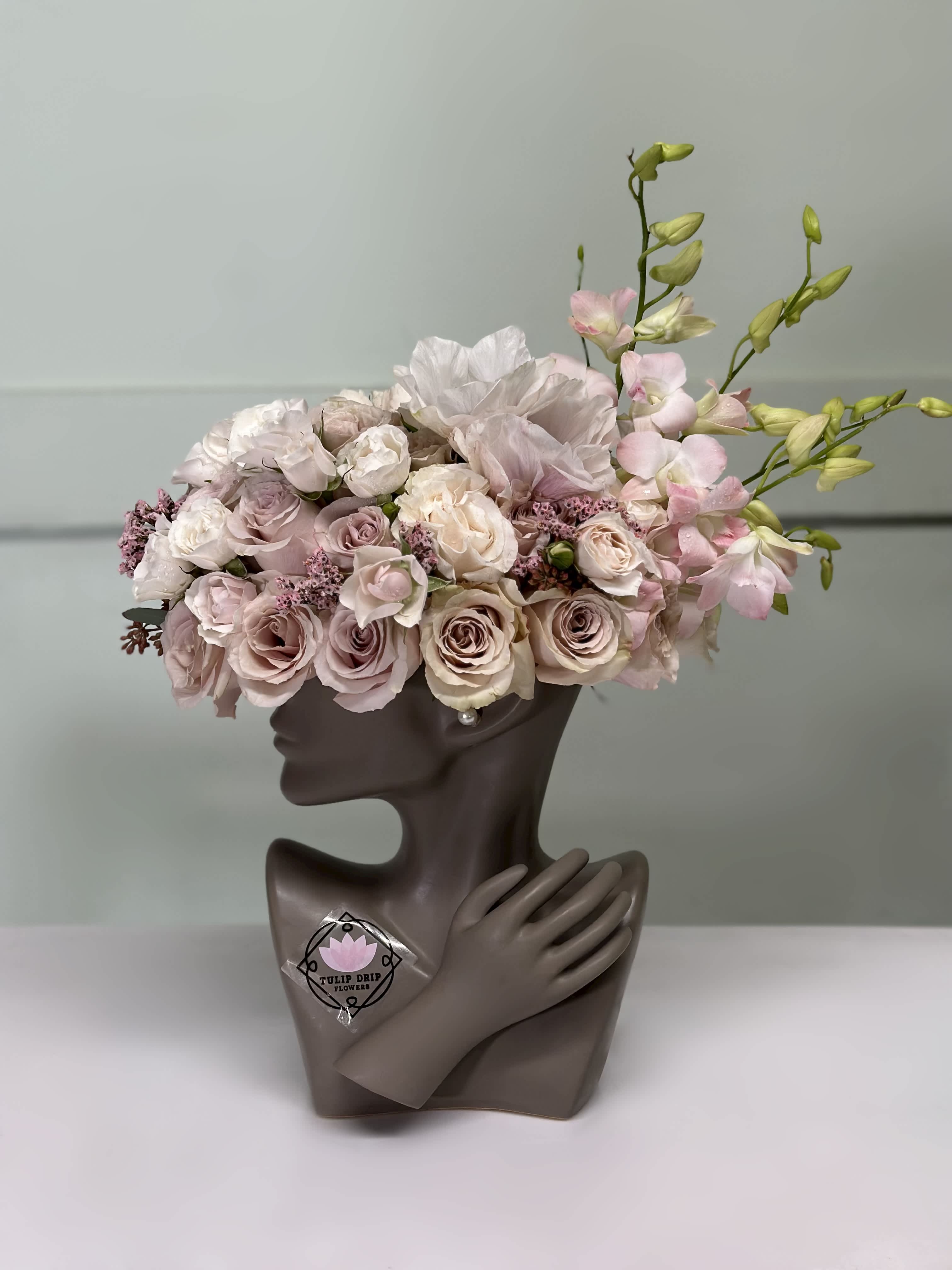 Pink and white floral arrangement in a sculptural bust vase